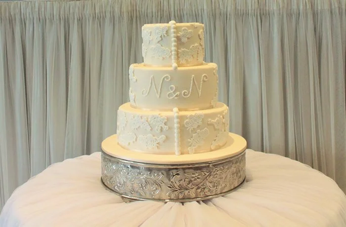 Elegant Lace with beading - This ivory iced cake is finished with beautiful pipework, lace and beading to give a truly elegant finish.