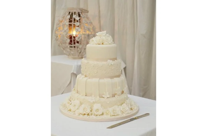 Ivory Rose Wedding Cake - This wedding cake is stunning with hand crafted ivory sugar roses and balanced with stripes, blossoms and piping detail.