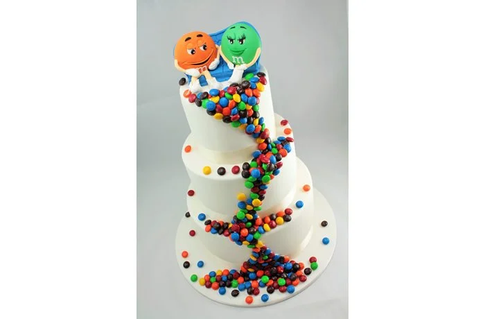 M&M Wedding Cake - Weddings are such a wonderful celebration. So why not have a bespoke wedding cake? This fun M&M cascade novelty cake will have your guests talking years after the big day.