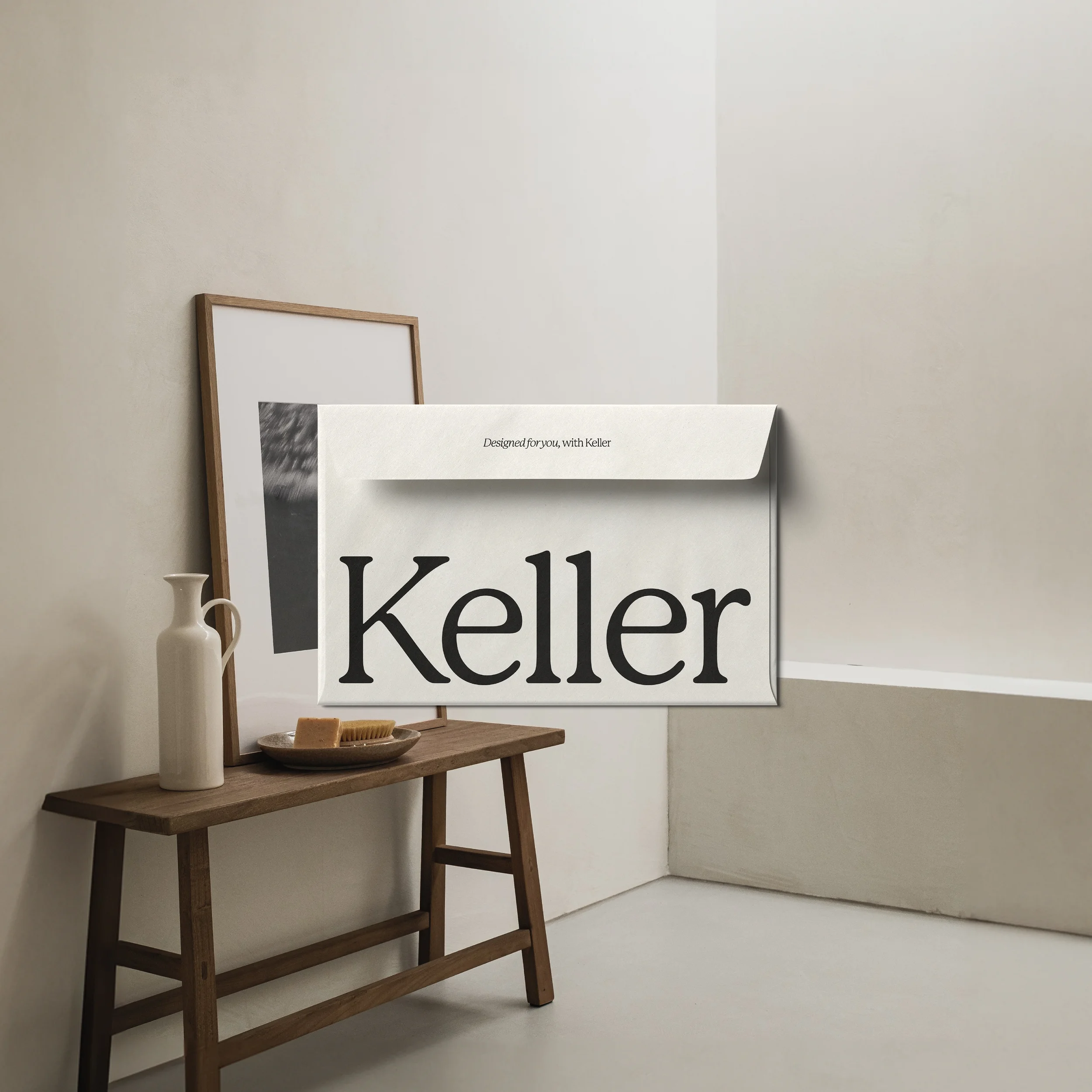 Keller branded mailing envelope with serif logotype and 'Designed for you' tagline, styled on a wooden bench.