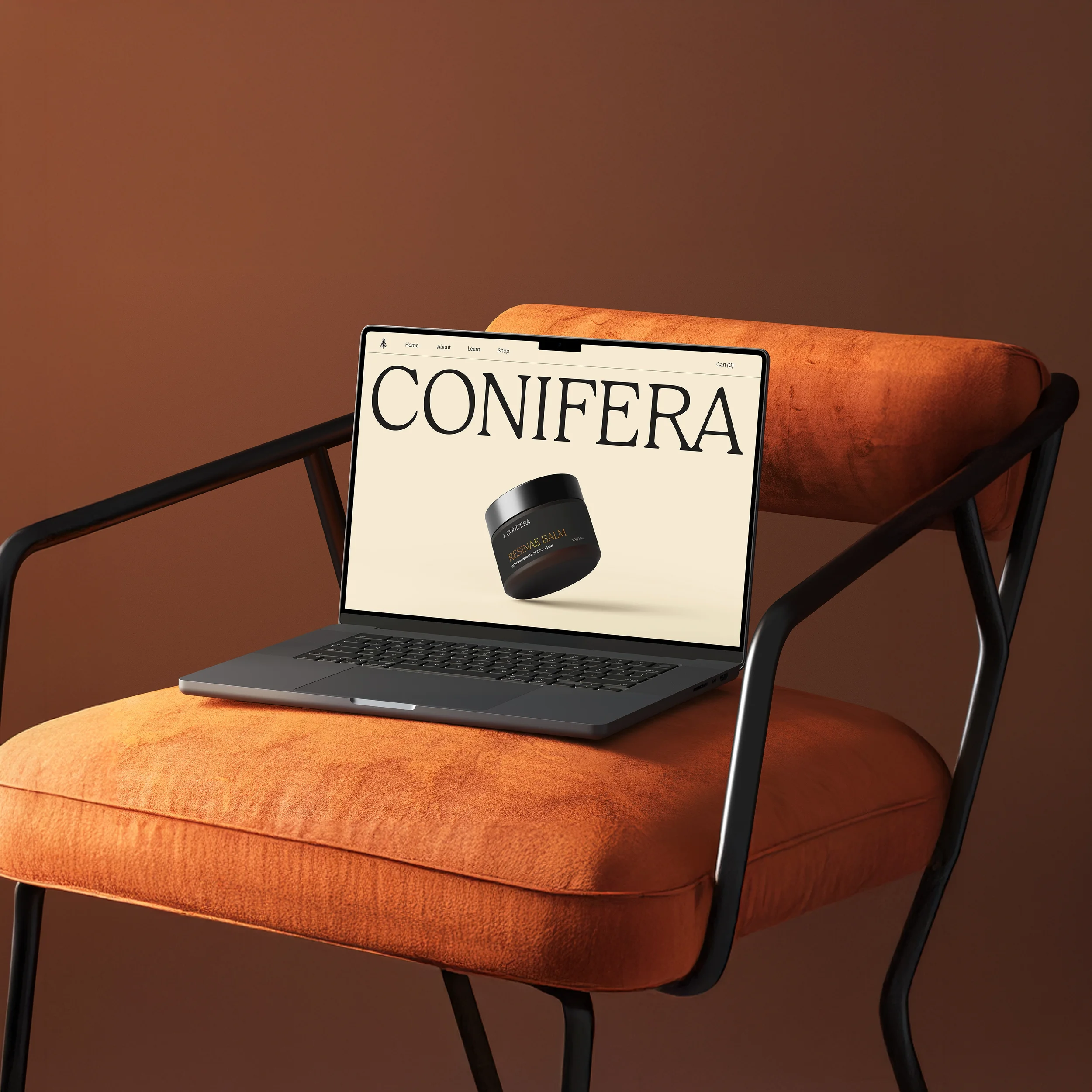 Conifera website homepage displayed on a laptop, showing the brand logo and Resinae Balm product, resting on a burnt orange velvet chair.