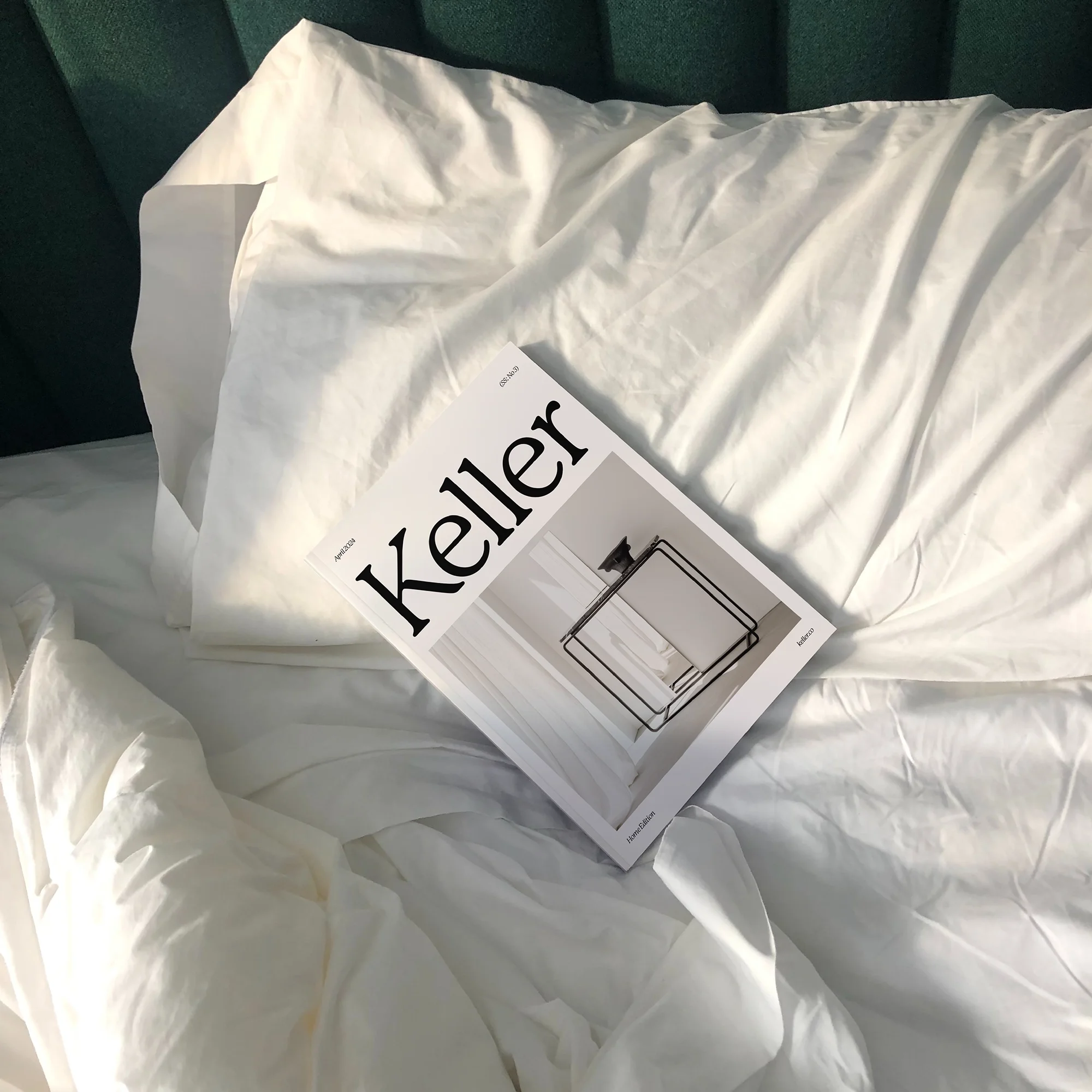 Keller magazine Home Edition cover featuring a serif logo and minimalist furniture photography, resting on white bed linen.