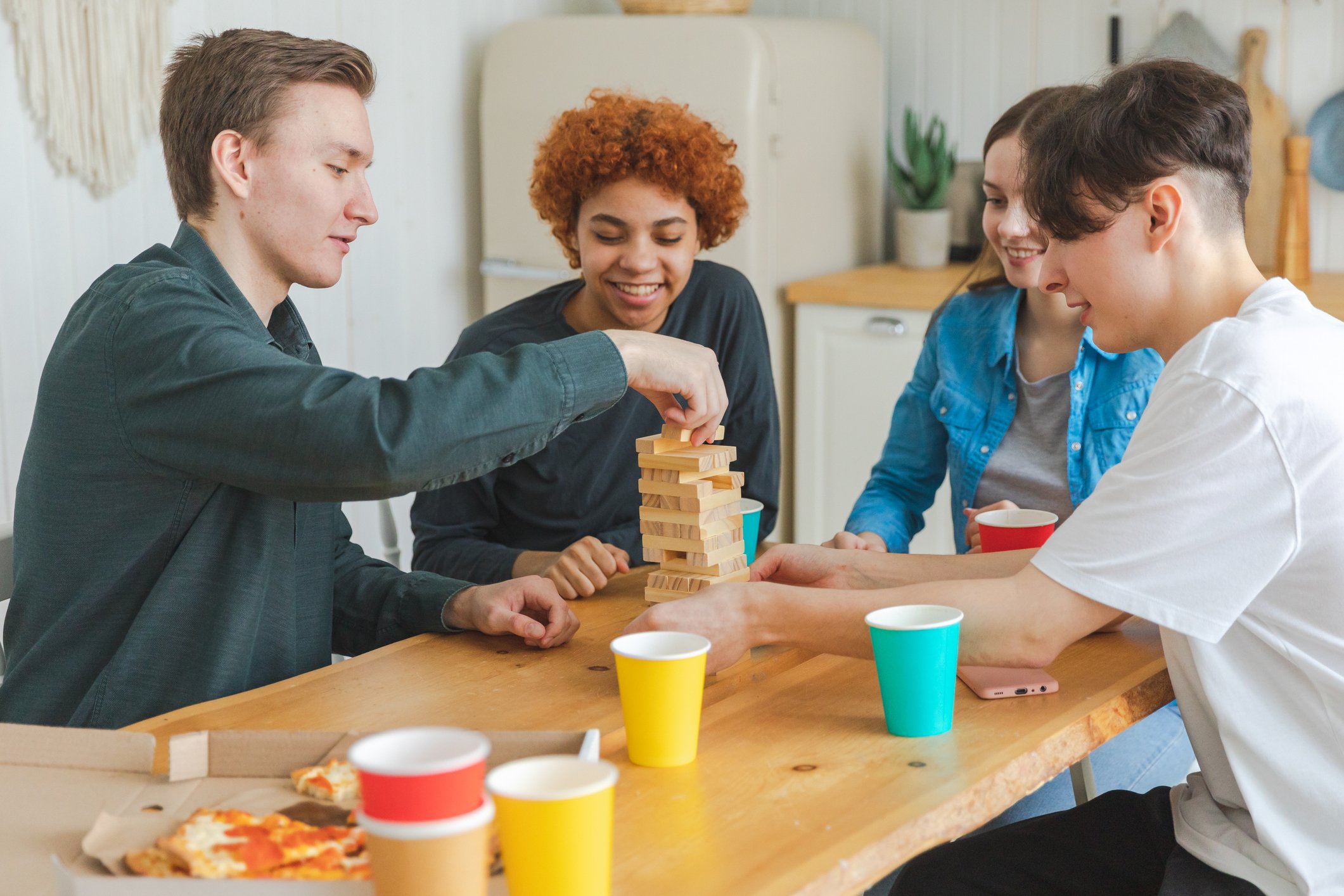 Homeschool students laughing and playing a tabletop game together during a daytime social group.