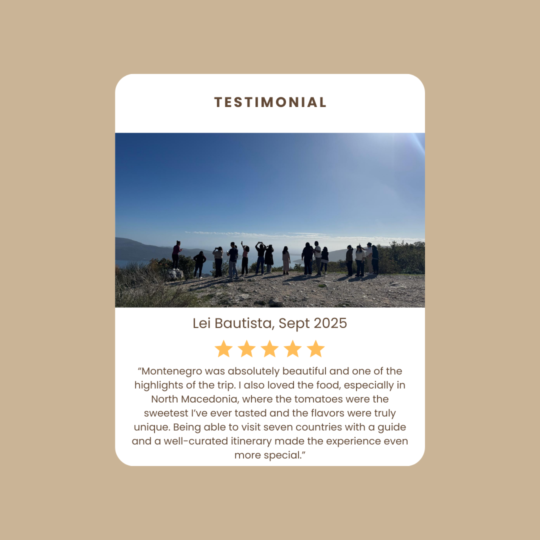 A group of people standing outdoors on a hill overlooking a body of water and mountains under a clear blue sky, with some taking photos and others chatting, in a testimonial card design.