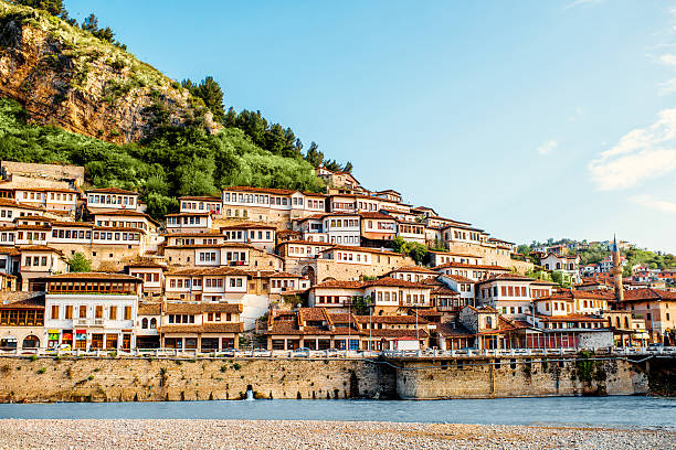 Houses built on a hillside overlooking a river, with a clear sky.