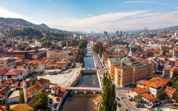 Aerial view of a city with a river running through downtown, surrounded by buildings and hills in the background.