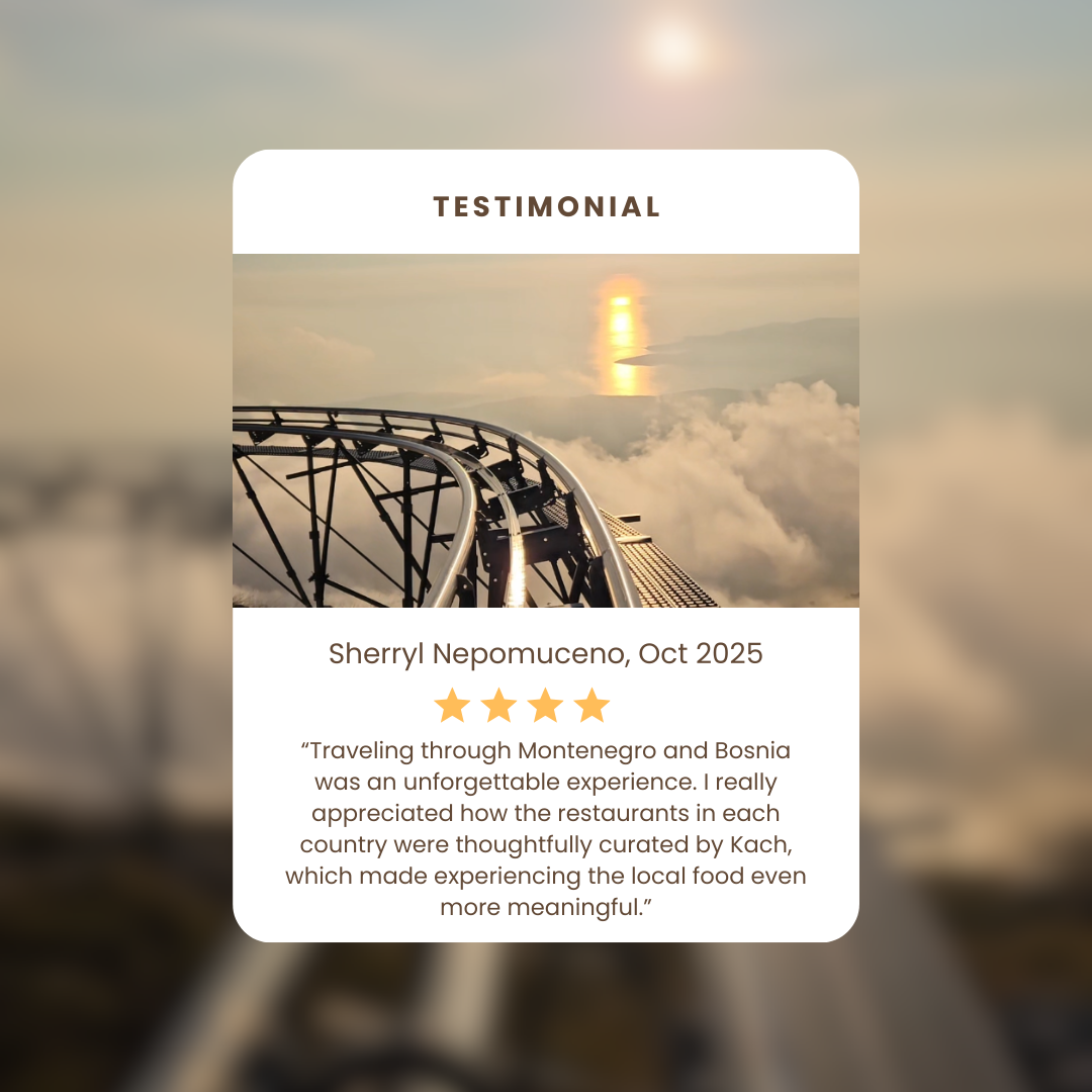 A scenic view of a roller coaster track extending over clouds with a sunset reflecting on water below.