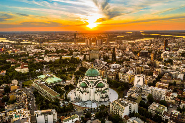 Aerial view of a cityscape at sunset featuring the Alexander Nevsky Cathedral with its green domes in the foreground.