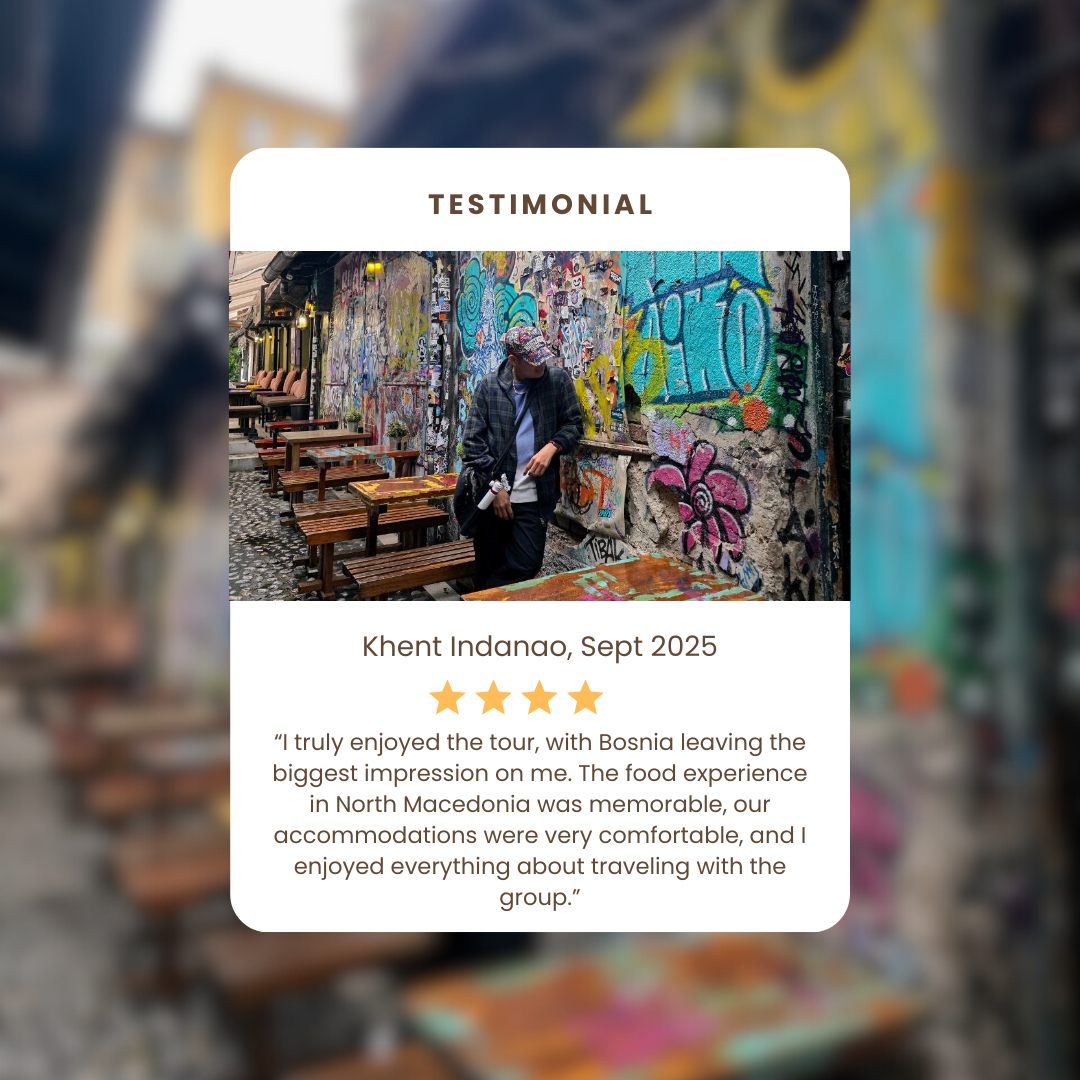 A person walking past graffiti-covered walls with outdoor wooden benches and tables in an urban setting.