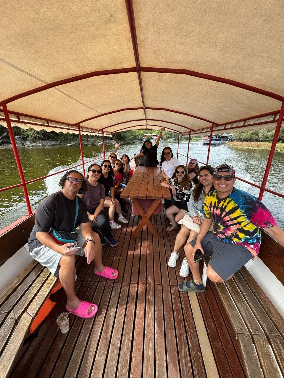 A group of people on a boat enjoying a boat ride on a river, with trees and another boat in the background in Lake Skadar, Montenegro.