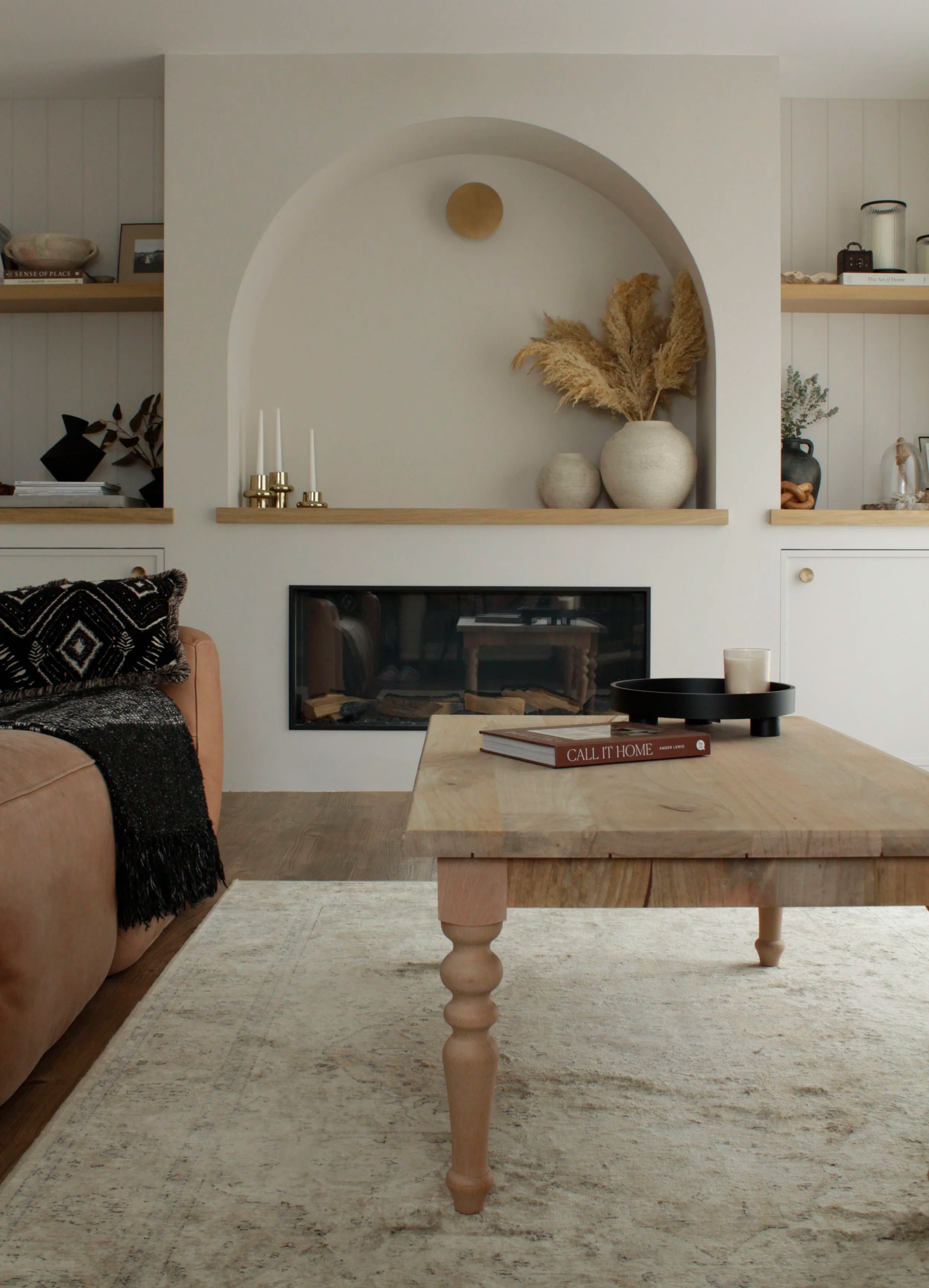 Modern farmhouse living room featuring a bespoke built-in fireplace wall with arched opening, oak shelving and integrated storage.