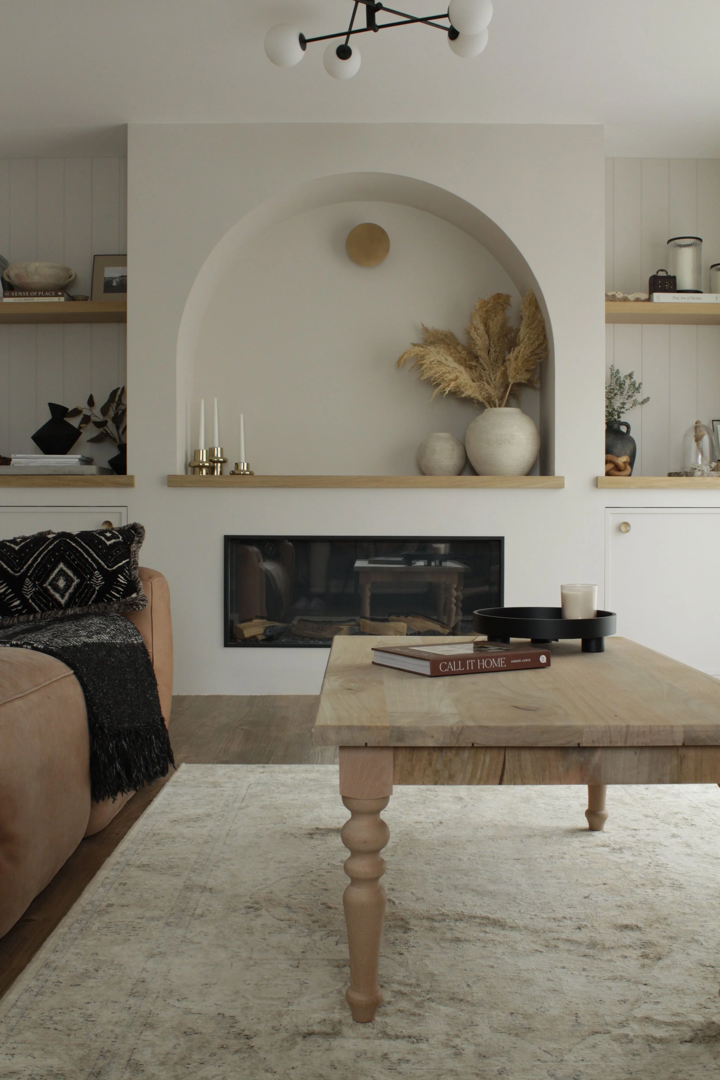 Modern farmhouse living room featuring a bespoke built-in fireplace wall with arched opening, oak shelving and integrated storage.