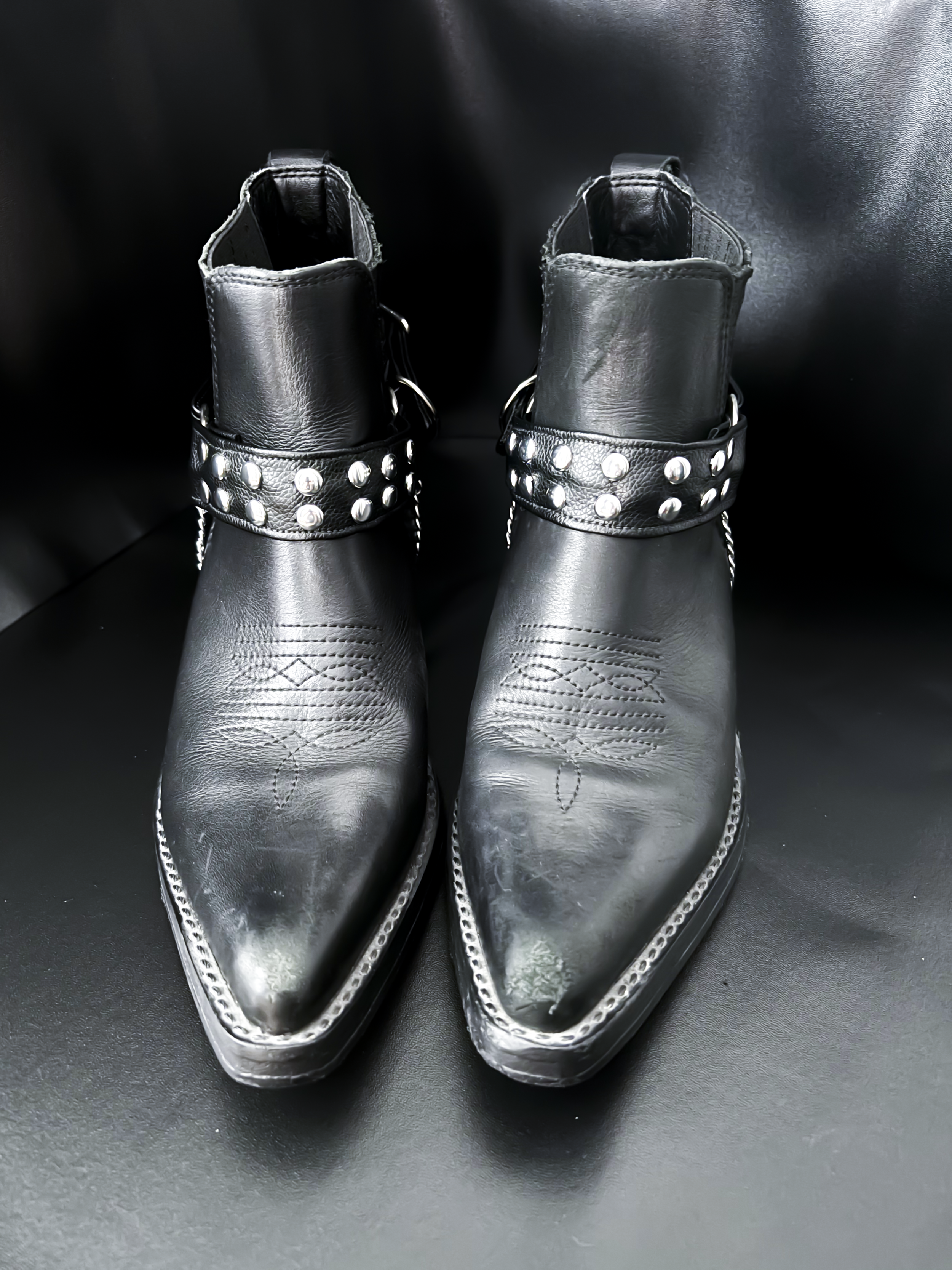 Chain looped beneath the front strap. Two styling options in one design—subtle but commanding. Round studs reflect light for a striking effect on stage or in everyday wear.