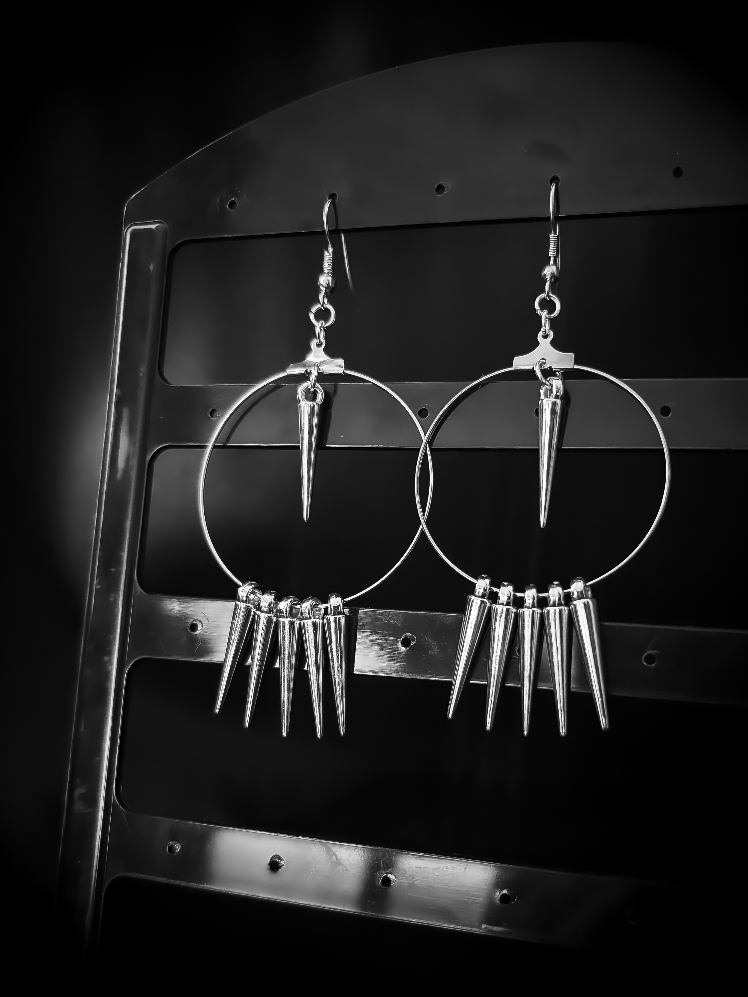 Spiked Reverie earrings on a hook display against matte black, spikes angled to catch every glint.
