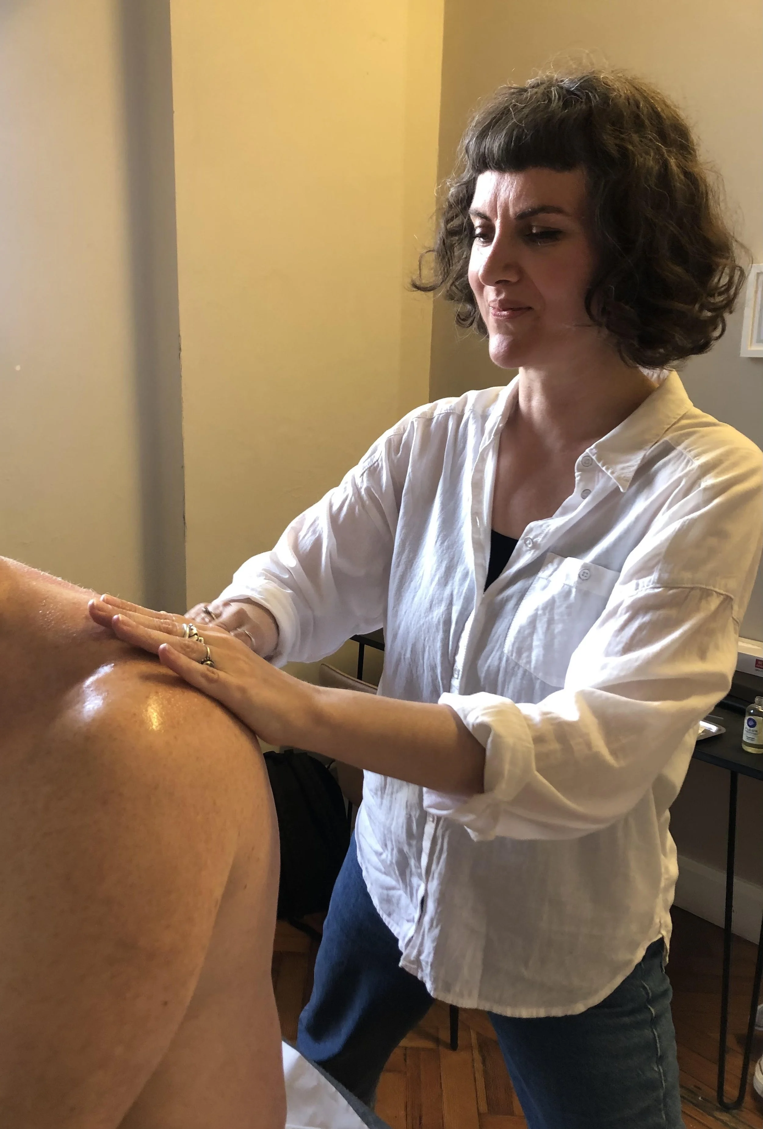 Annette Malone in a white shirt providing guasha to a person with bare back in a room. Acupuncture. Clapton. E5. Core. Healing Space
