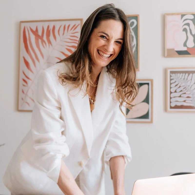 A young woman, smiling big, dressed in a clean white suit.