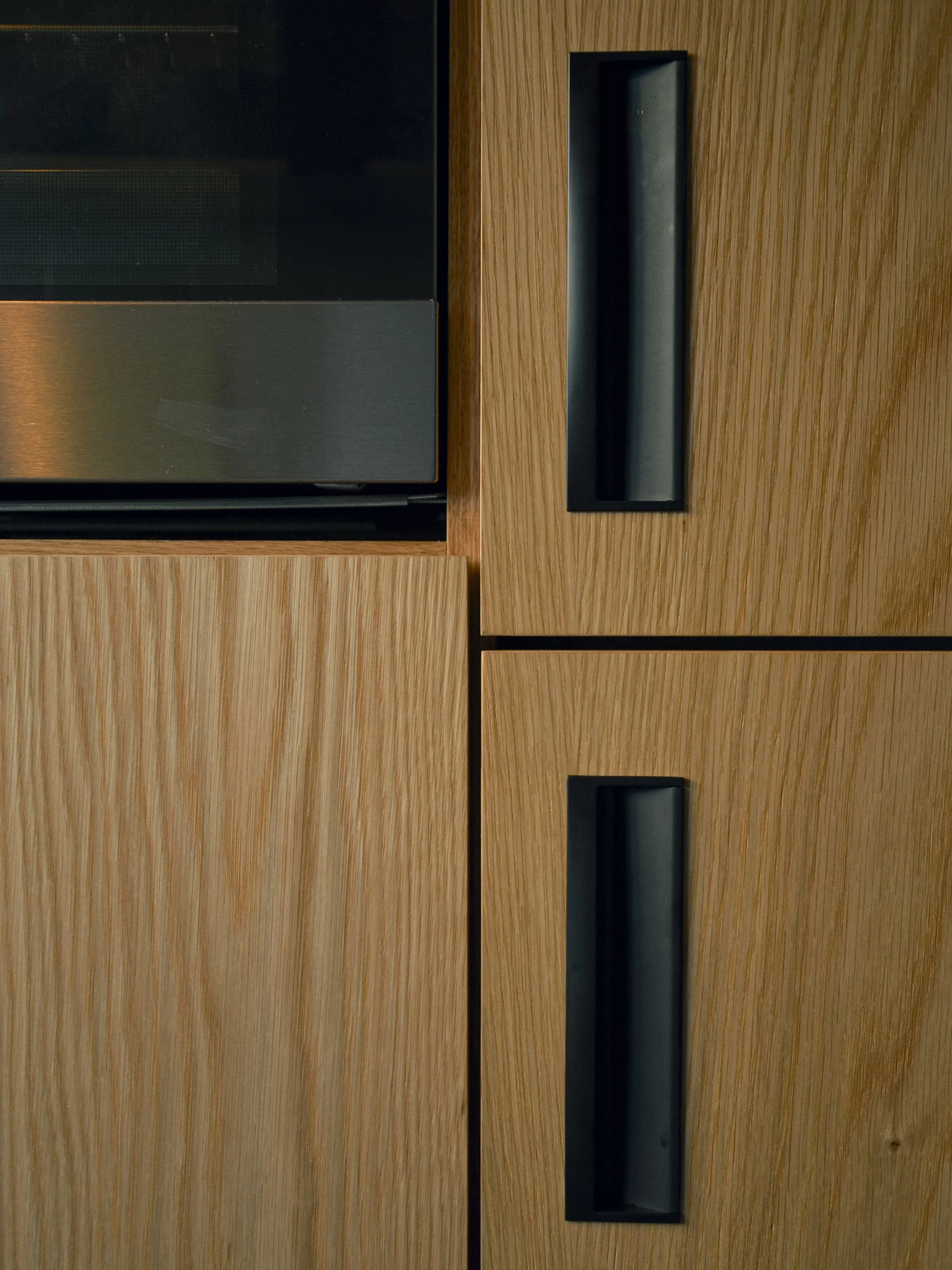 Armários com eletrodomésticos encastrados, folheados a carvalho americano, com elementos em ferro termolacado.