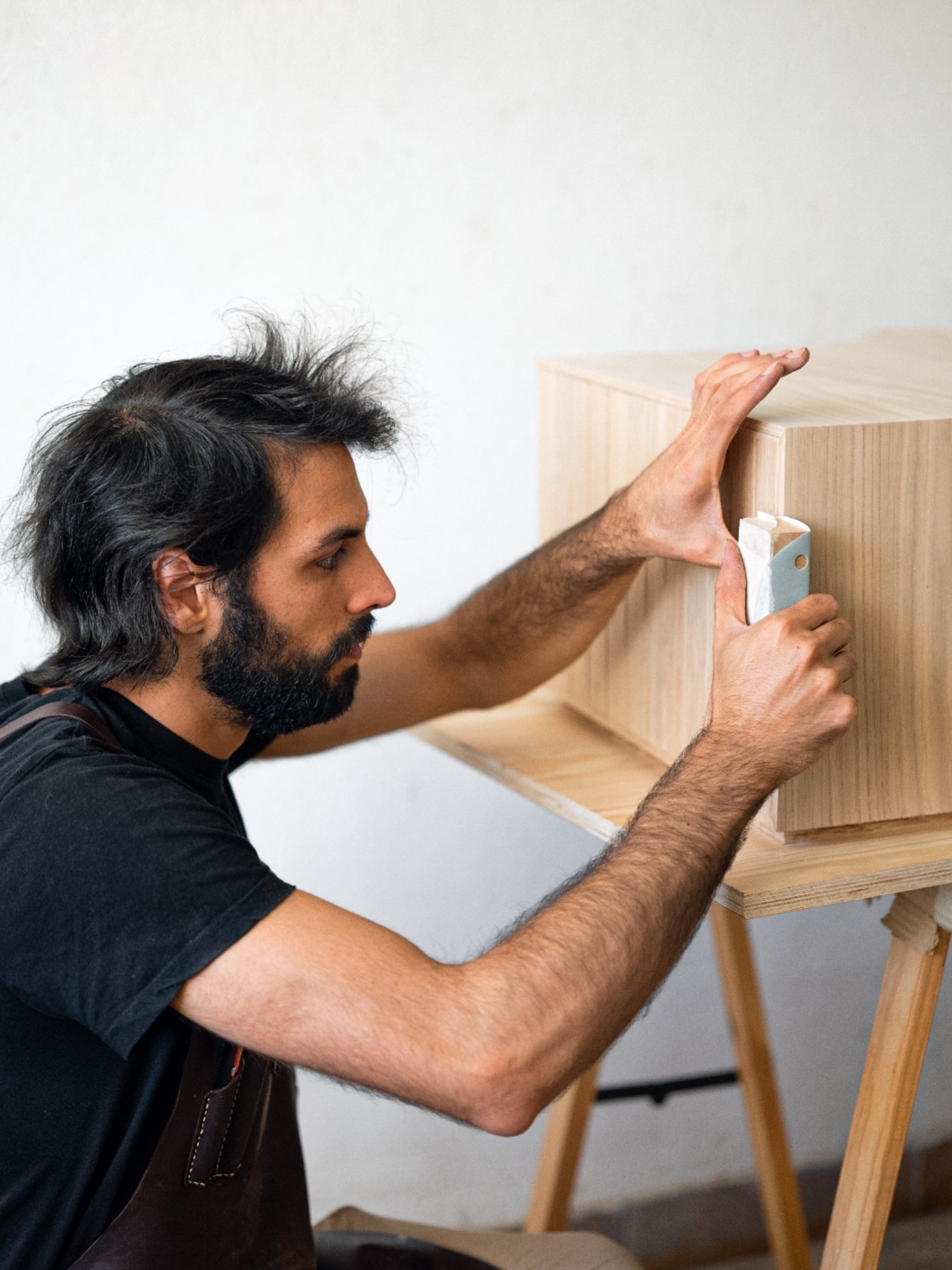 Manel a lixar uma peça de madeira no atelier da Nó.