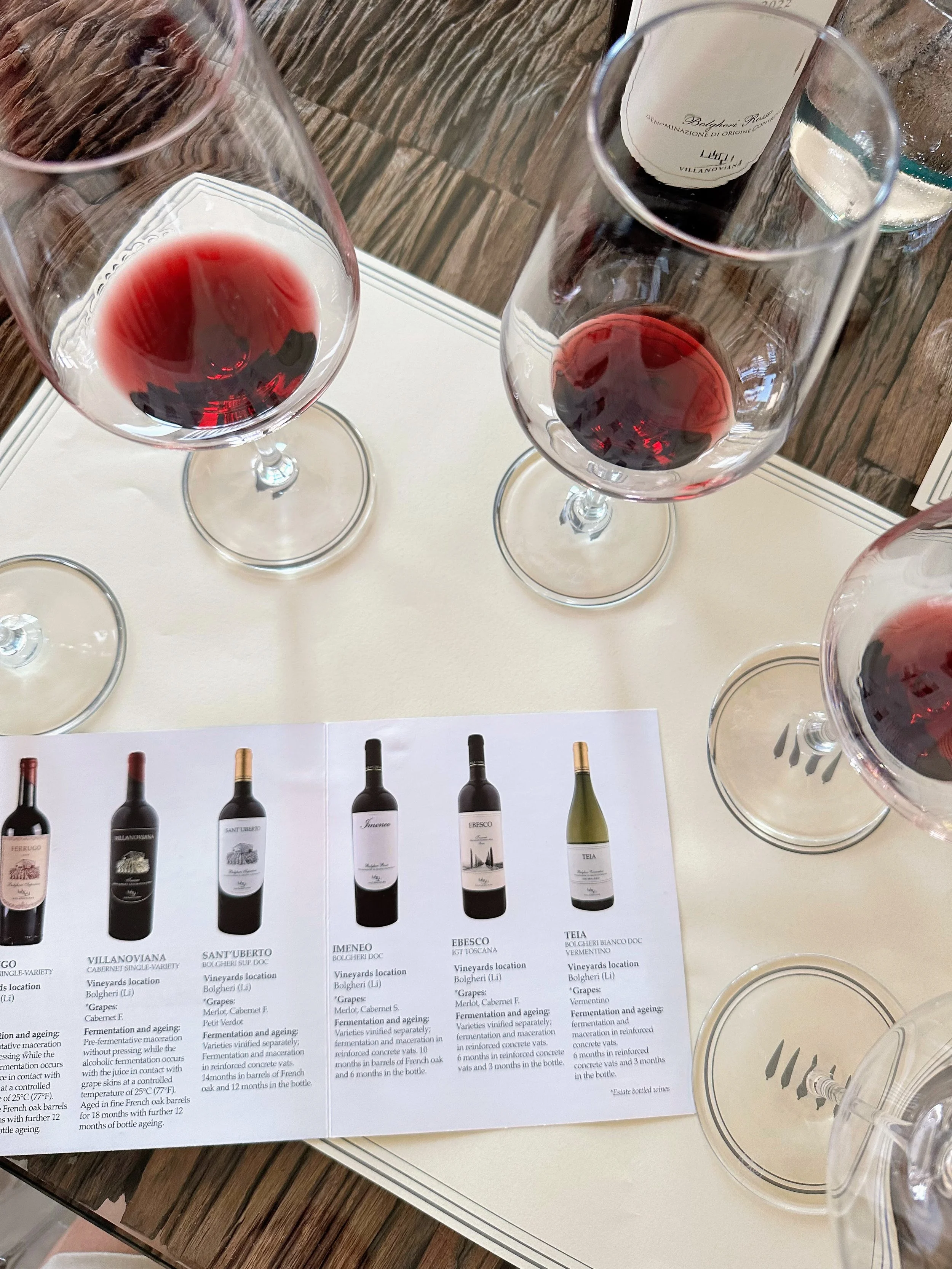 Three glasses of red wine and a wine tasting guide on a table.