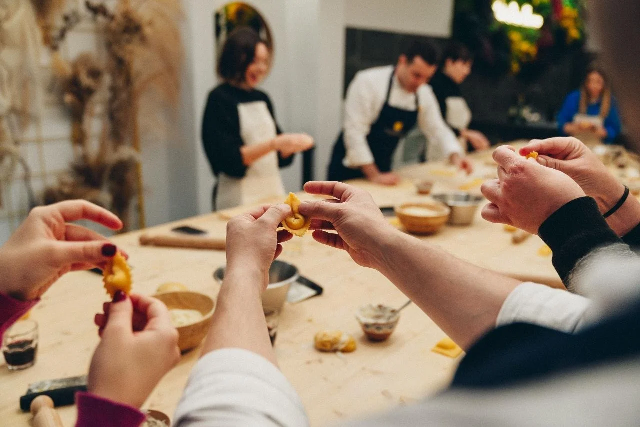 People making pasta at a cooking class with instructors in the background