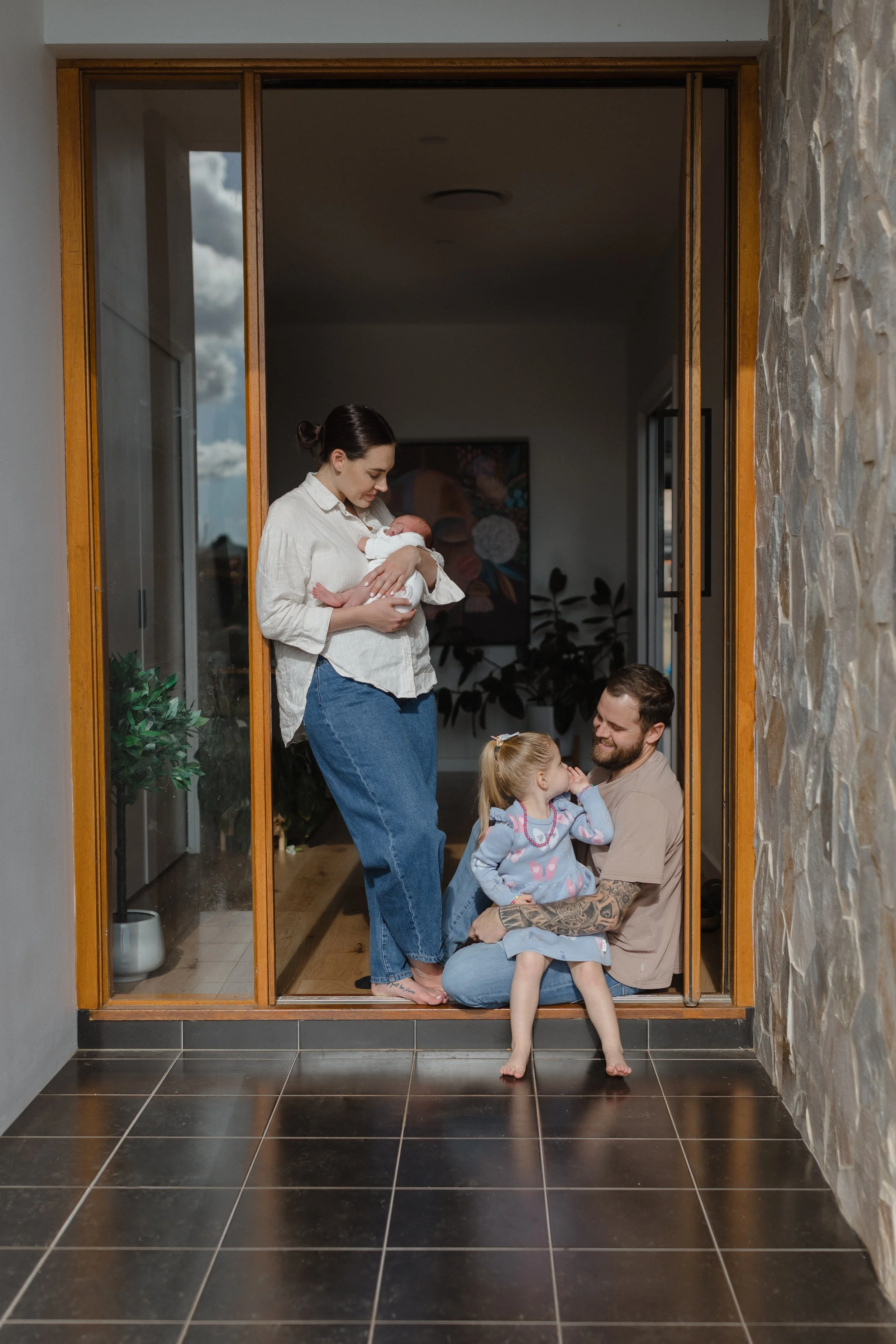 newborn-family-photoshoot-doorway-cuddles-toddler-smiling.jpg