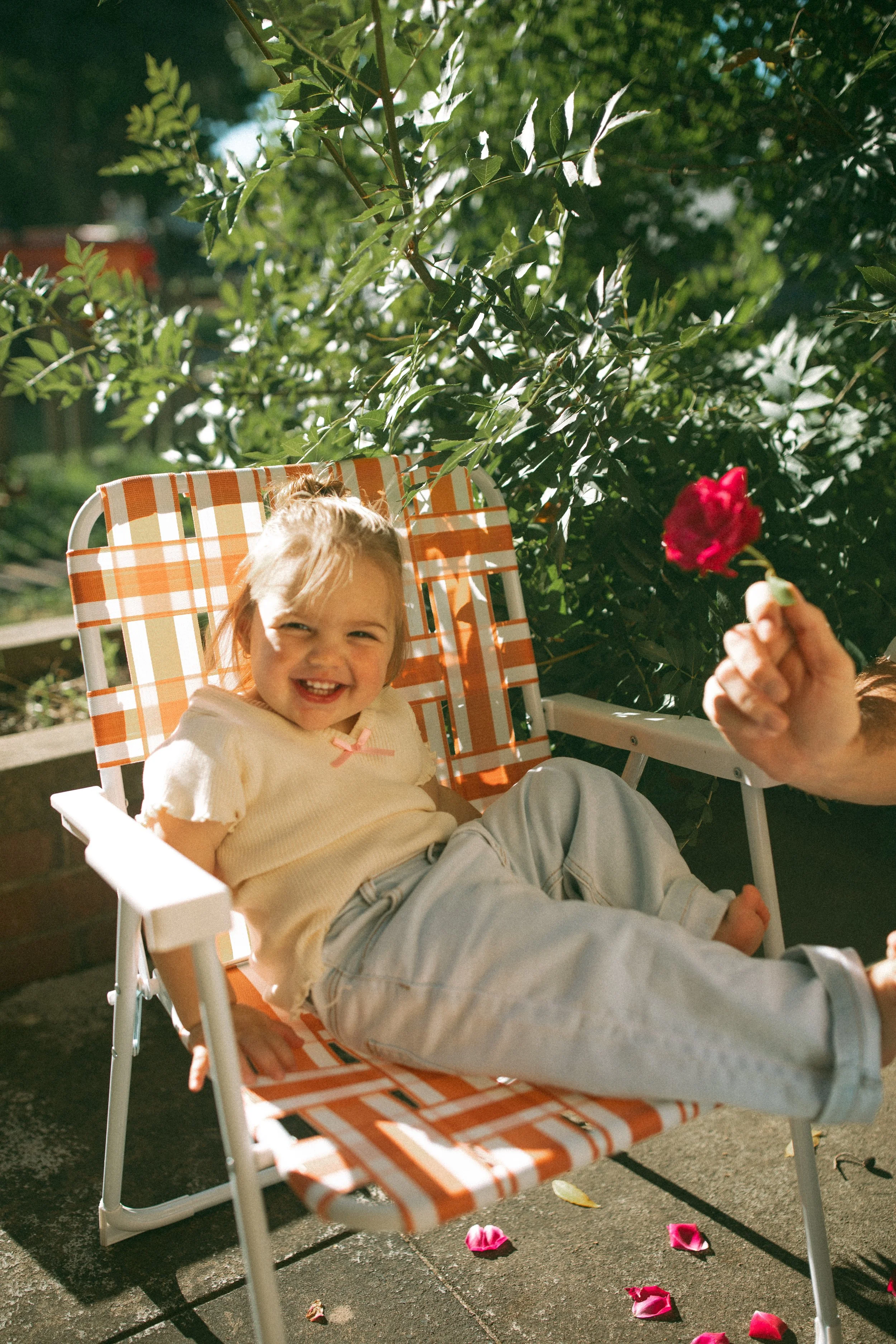 toddler-portrait-retro-chair-sunlit-flower-petals.jpg