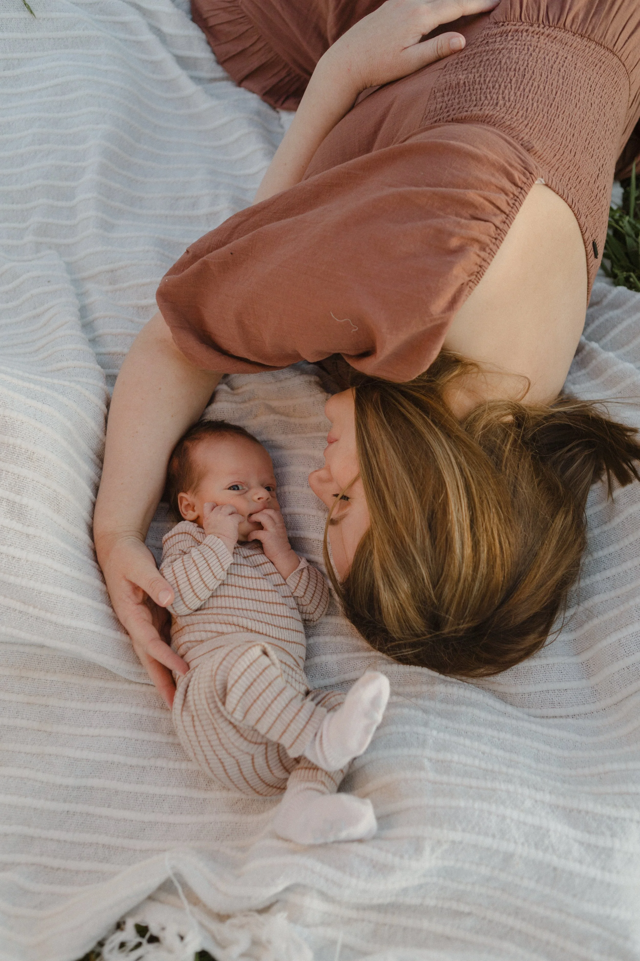outdoor-newborn-photography-mother-cuddling-on-blanket.jpg