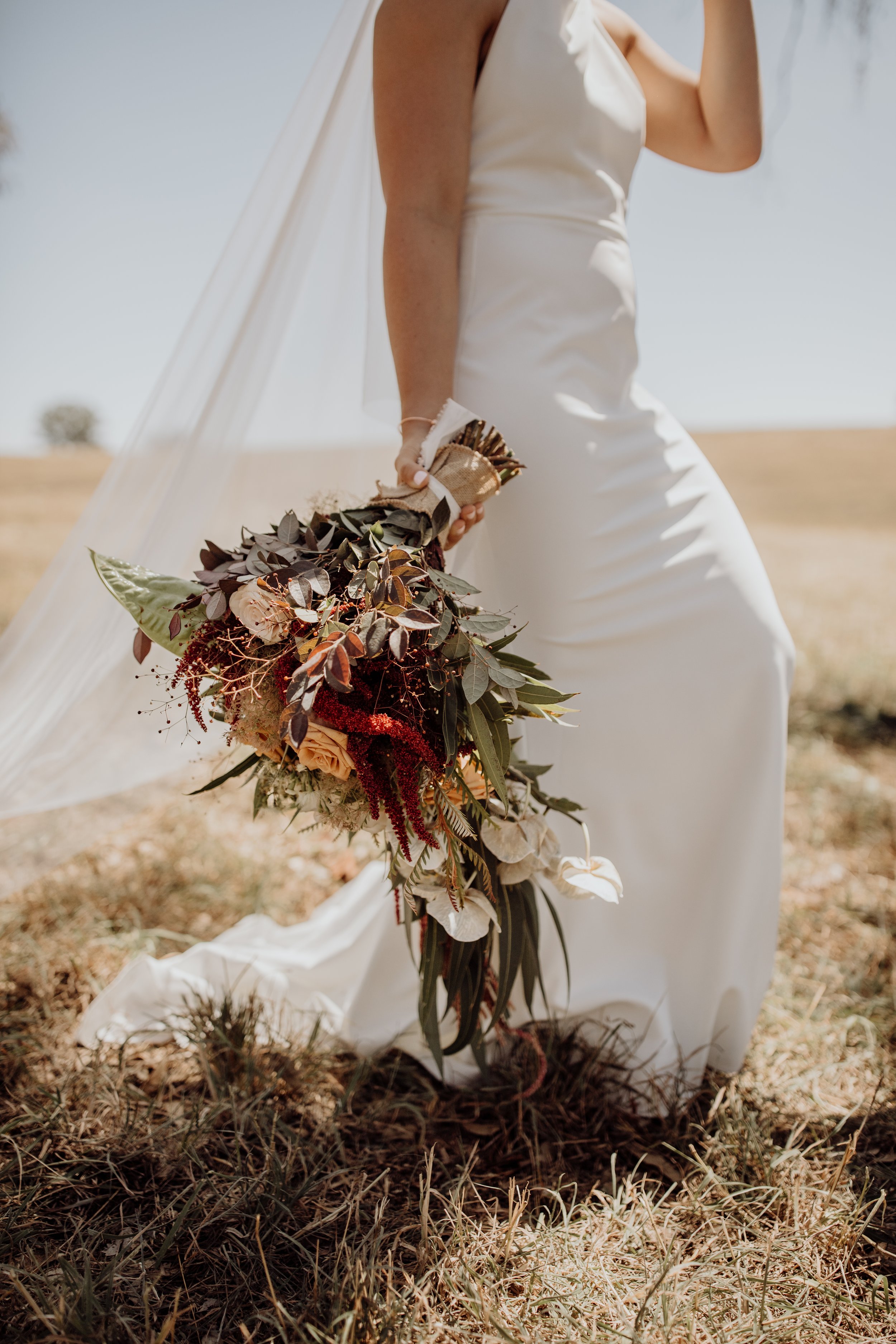 close-up-brides-dress-flowers-veil-outdoor-wedding.jpg