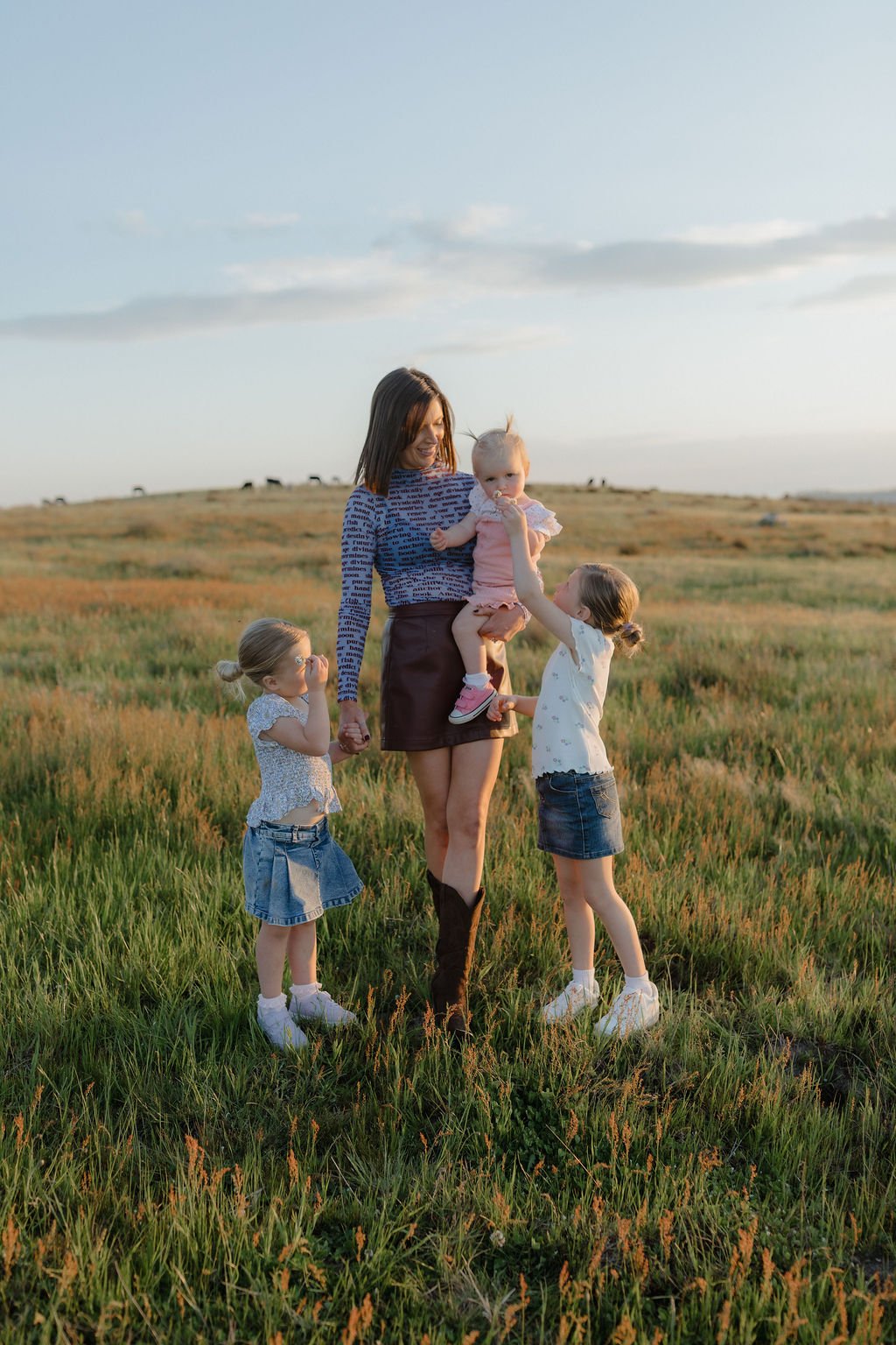 Mum sharing a joyful moment with her three daughters on their family farm during a relaxed family photography session by Jade Jones Photography.