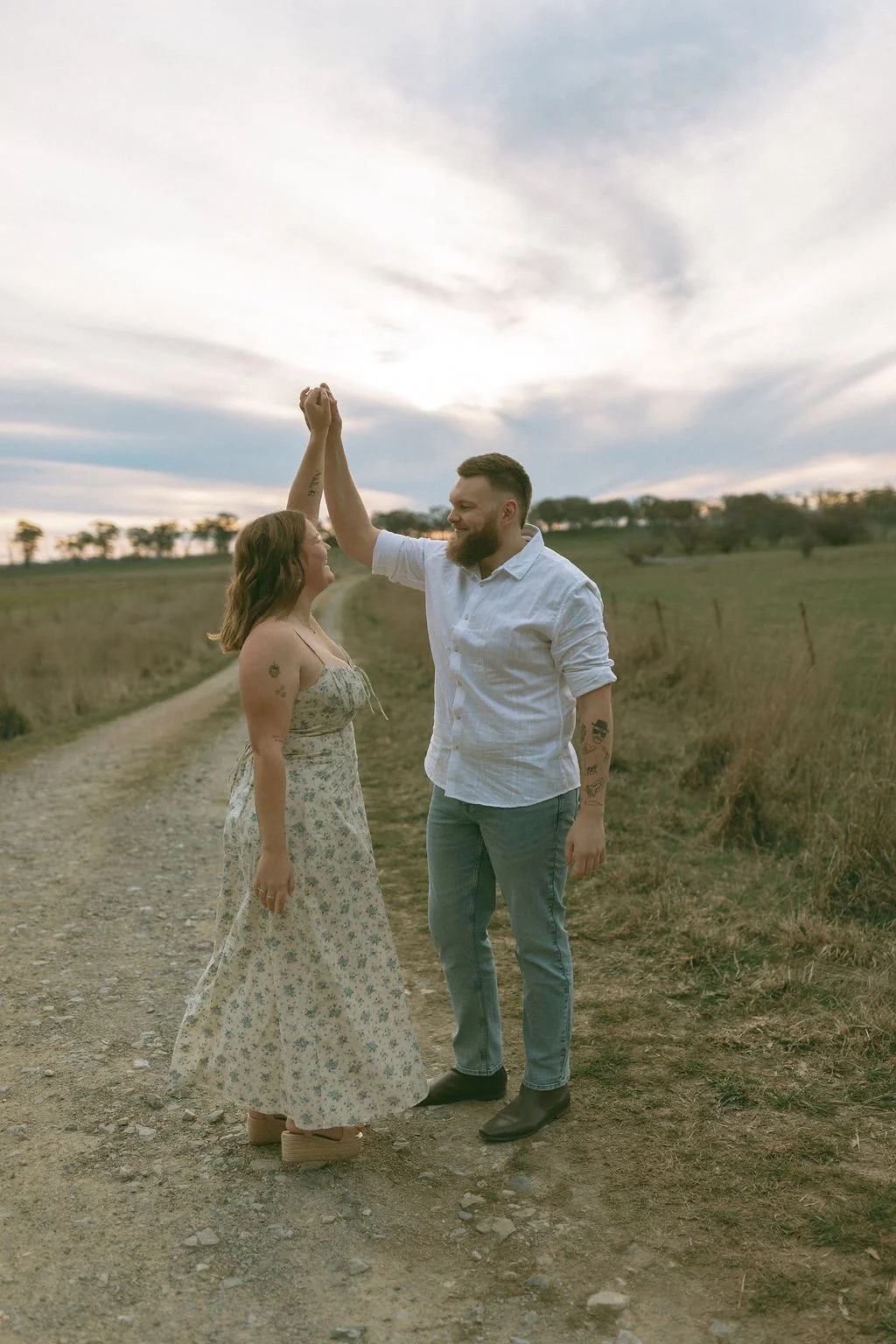 Engaged couple sharing a joyful moment as he spins her while holding her hand during a romantic engagement photoshoot.