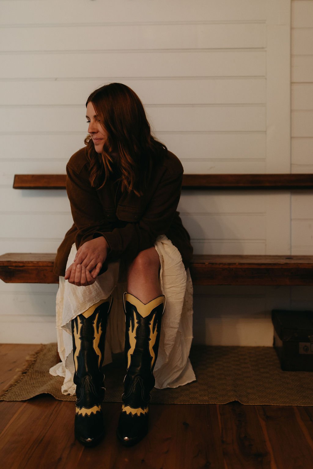Photographer Jade Jones sitting naturally in a flowy dress, brown jacket and cowgirl boots.