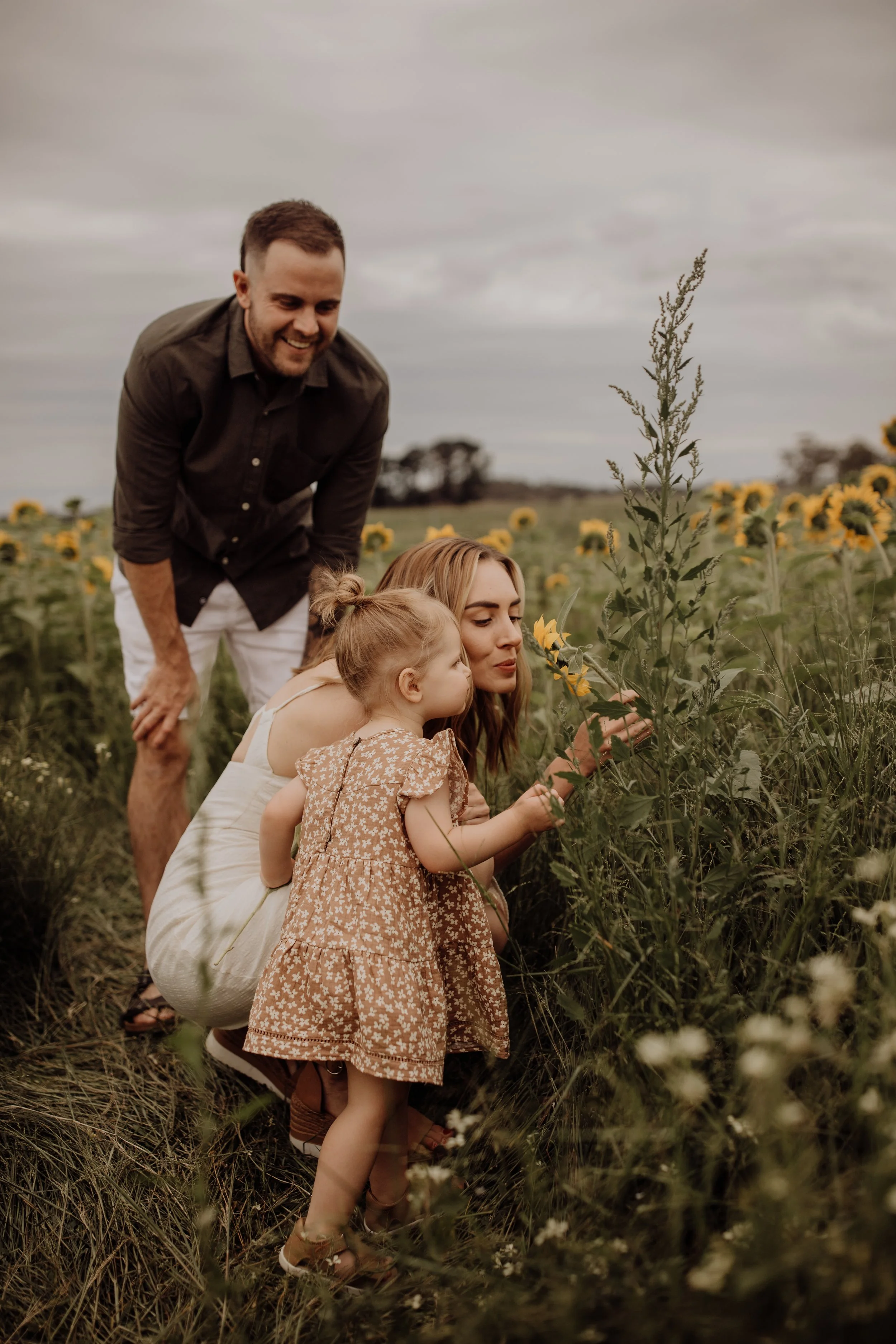 family-photoshoot-sunflower-field-mother-toddler-smelling-flower.jpg