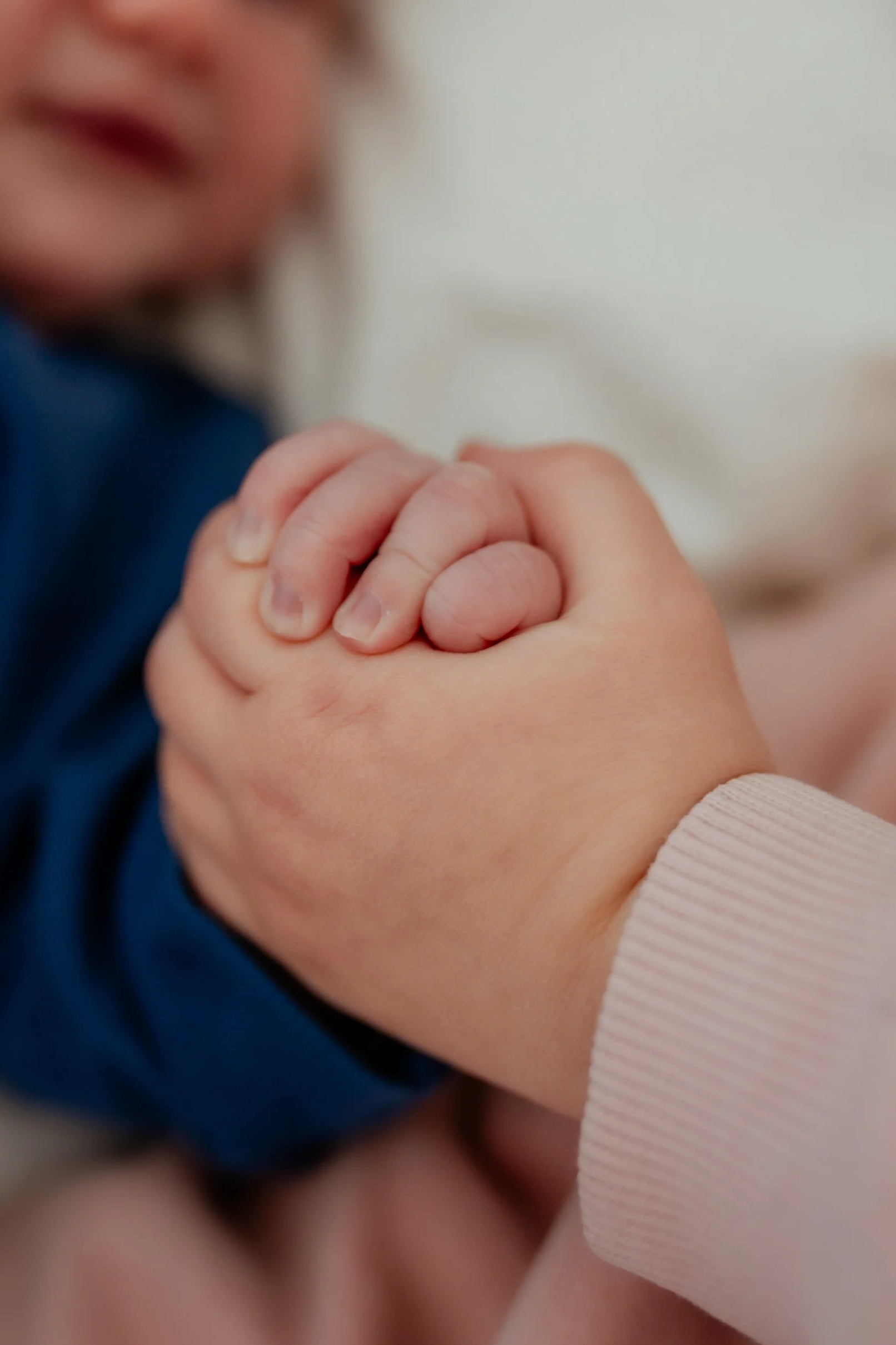 Gros plan sur deux mains d'enfant qui se tiennent, une main étant celle d'une personne plus âgée, l'autre celle d'un enfant, avec un fond flou.