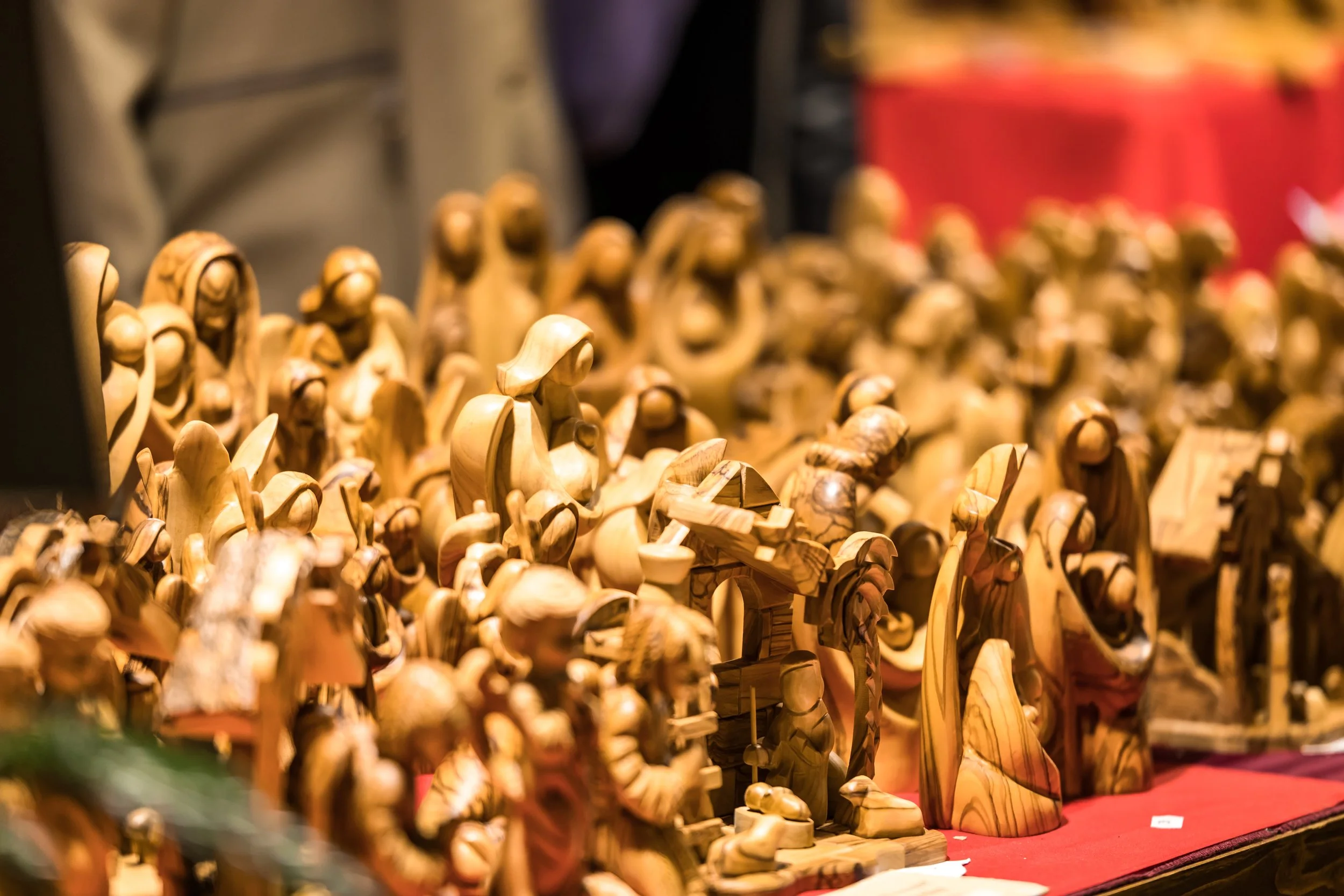 A display of carved wooden figurines on shelves at an art or craft exhibition.