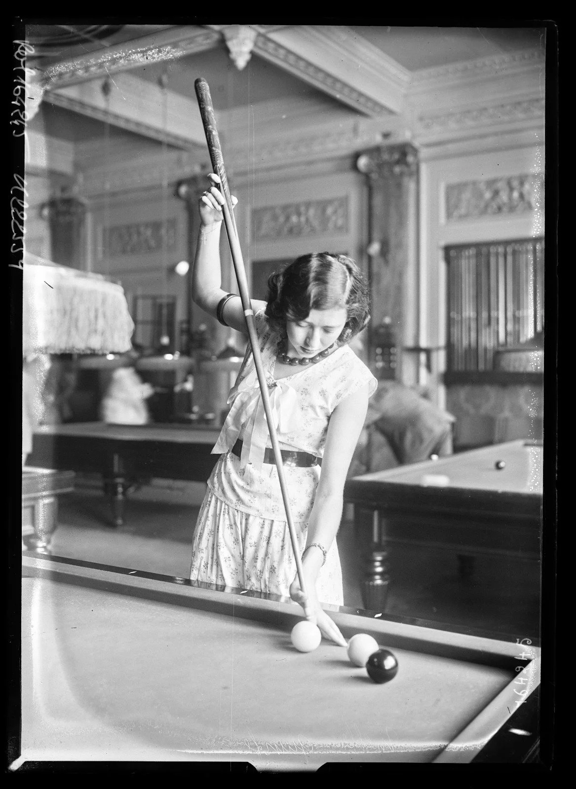 Sylviane d’Arbantès exécutant un coup massé au billard dans un établissement du boulevard des Capucines à Paris.