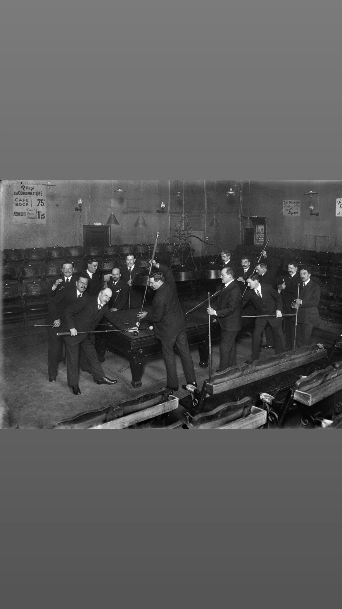 Quatorze joueurs de billard réunis à l’étage professionnel d’une salle de billard parisienne, autour d'une table de jeu.