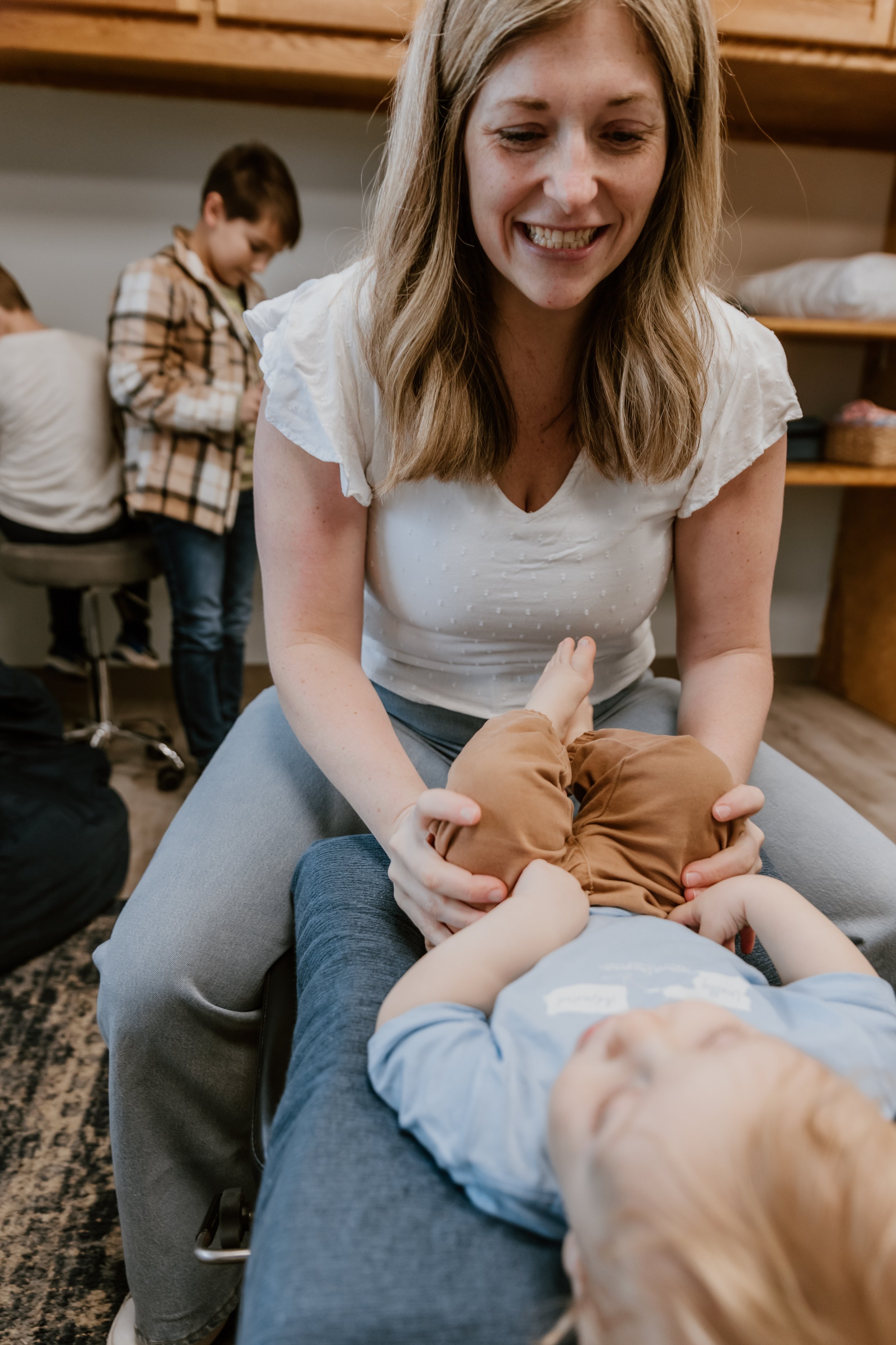 Woman smiling while adjusting a baby lying on a chiropractic table.