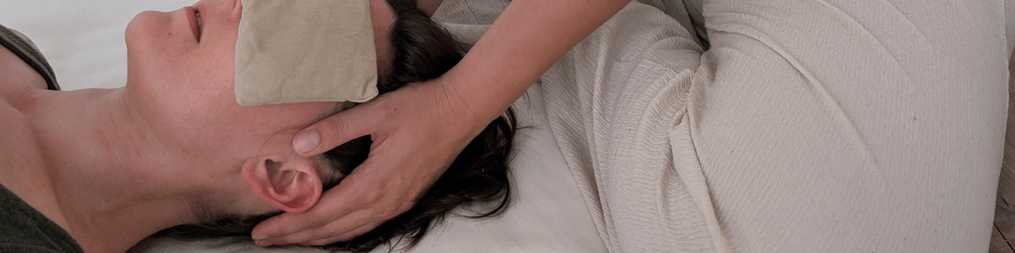 Woman lying on a treatment table receiving a neck and shoulder massage.