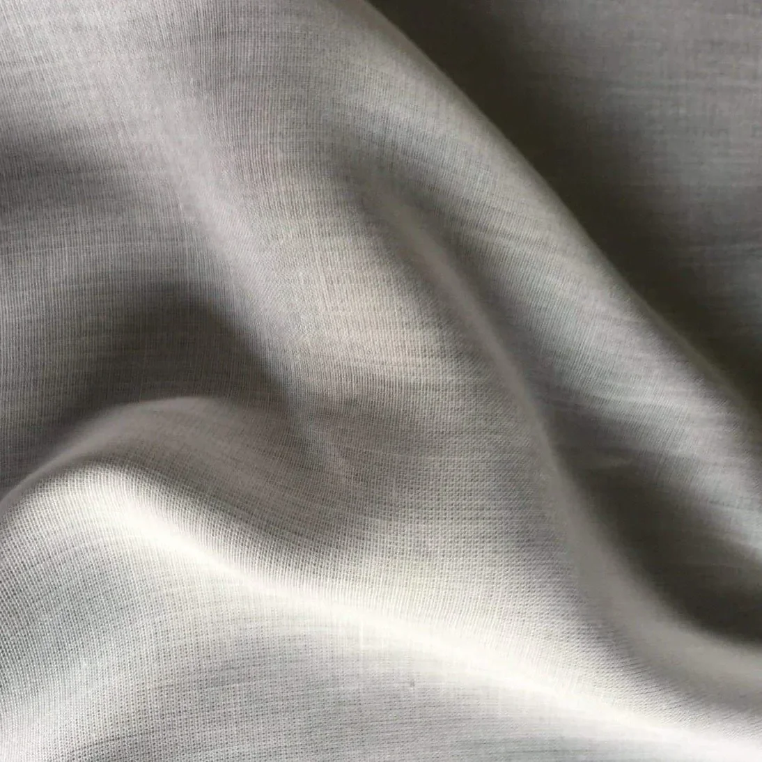 Close-up of smooth, shiny, gray fabric with soft folds.