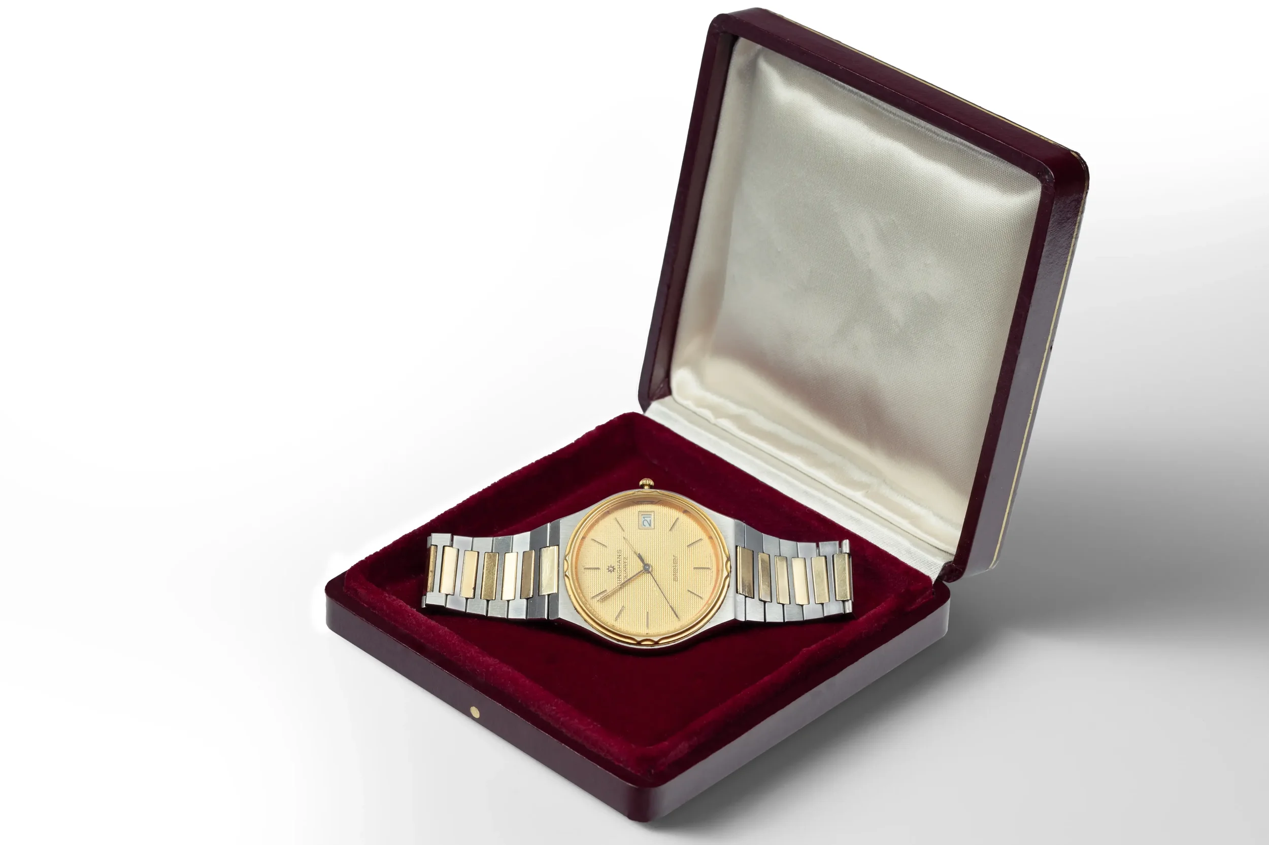 Eine goldene Armbanduhr in einer roten Samtkiste, die offen ist.