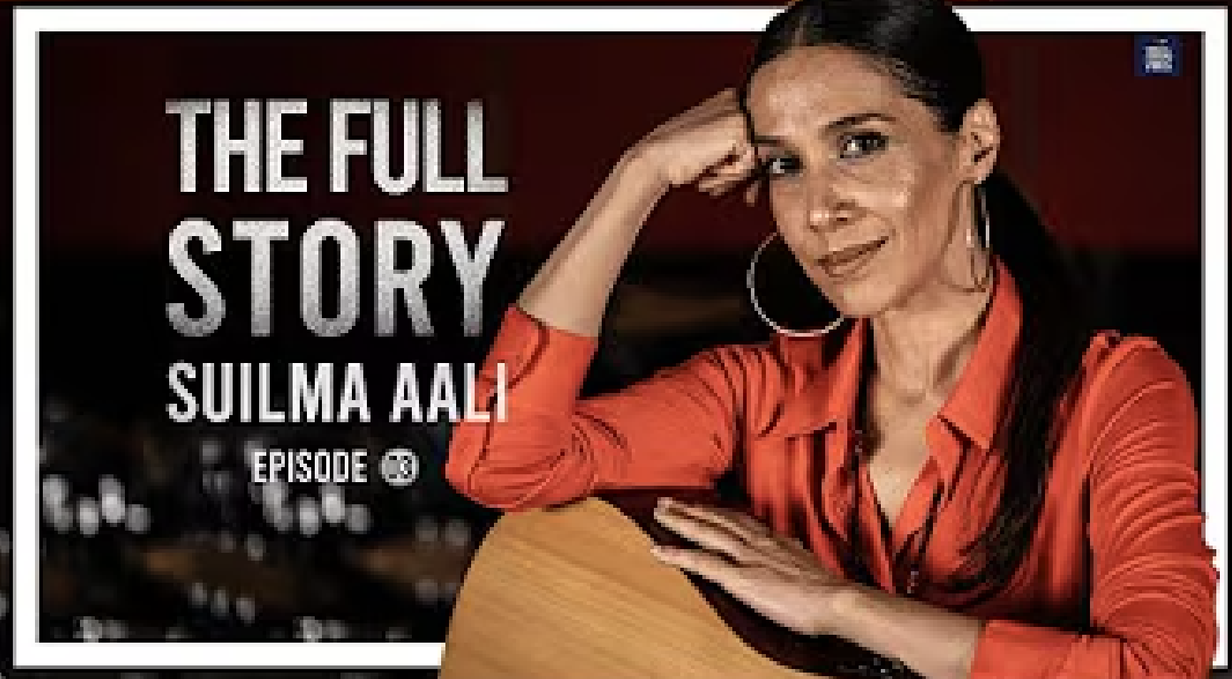 A woman with long dark hair, wearing hoop earrings and an orange shirt, resting her head on her hand with a guitar in front of her. Text reads 'The Full Story', 'Suilma Aali', and 'Episode 3'.