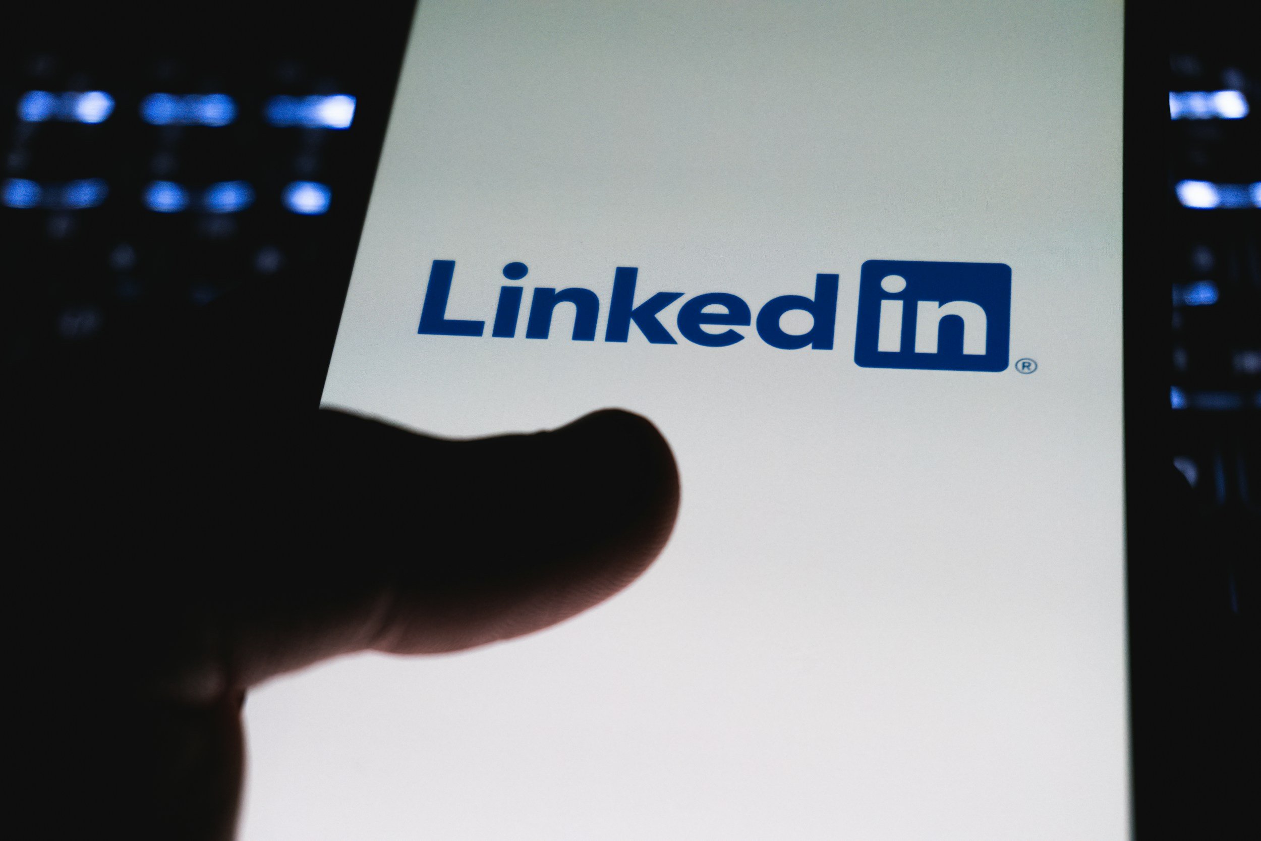 Person holding a smartphone with the LinkedIn logo displayed on the screen.