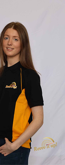 A young woman with long brown hair wearing a black and yellow polo shirt with a logo, standing against a plain white background.