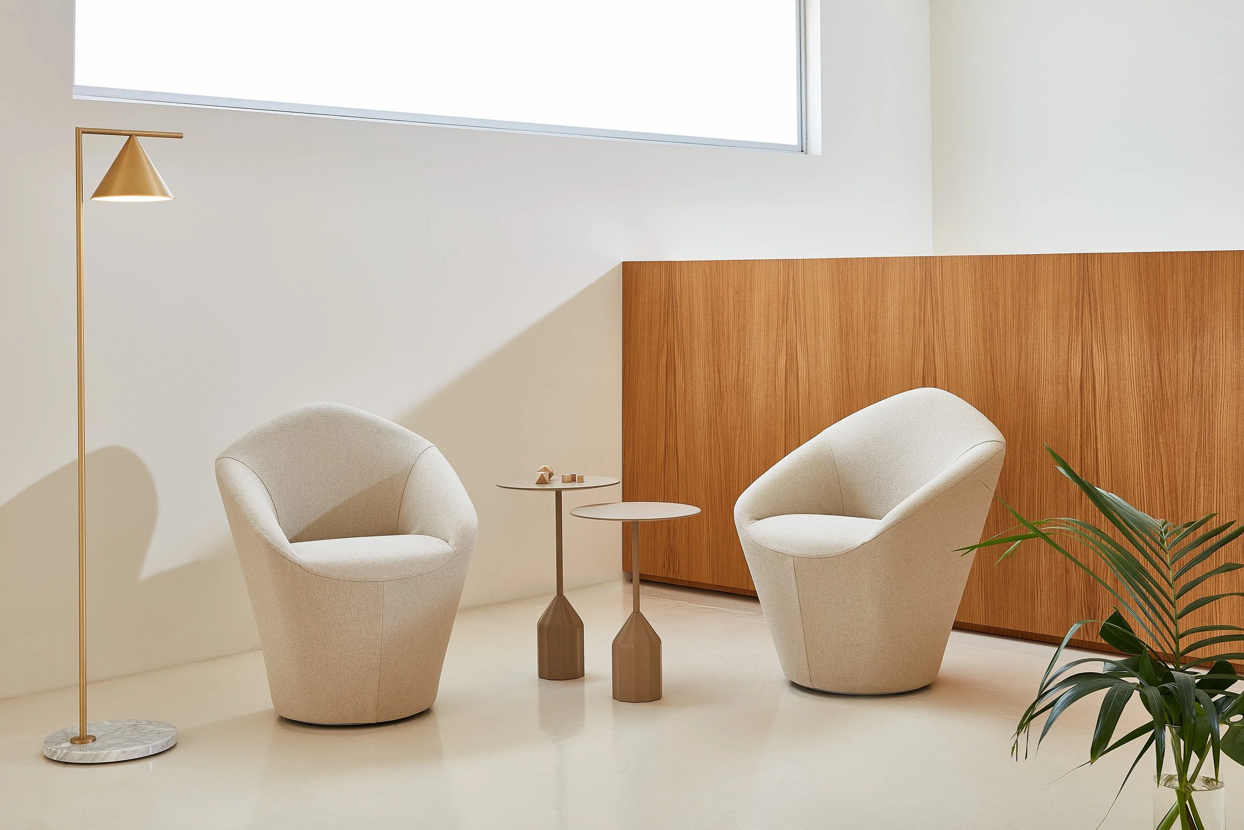 Minimalist seating area with two beige modern armchairs, a tall gold floor lamp, and two small side tables.