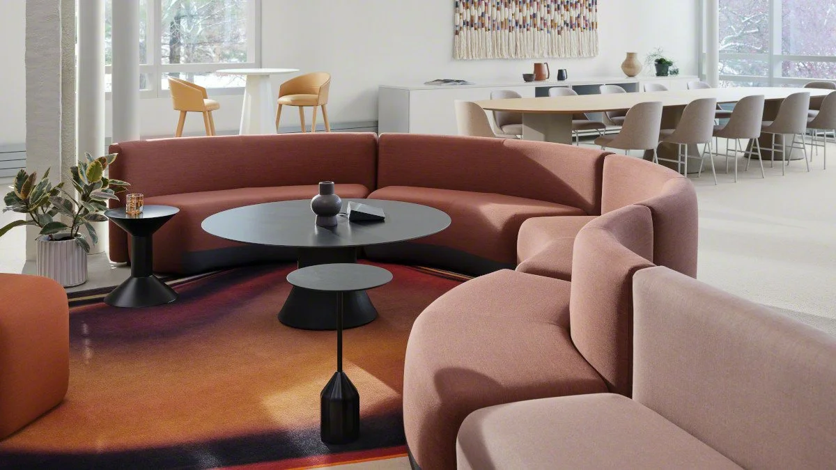Modern lounge area or lobby with pink sectional sofa and black coffee tables.