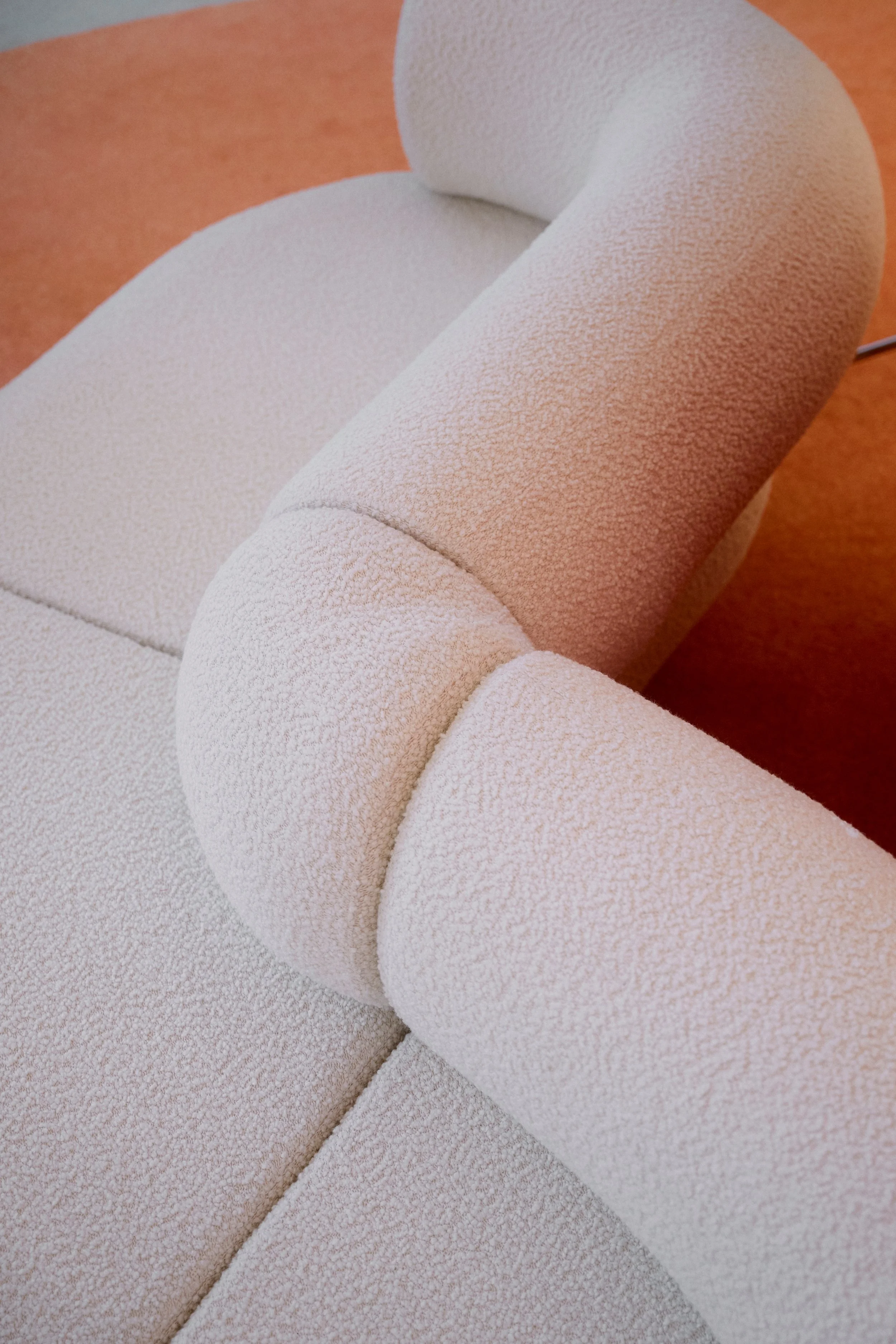 Close-up of a modern, textured beige sofa with rounded armrest.