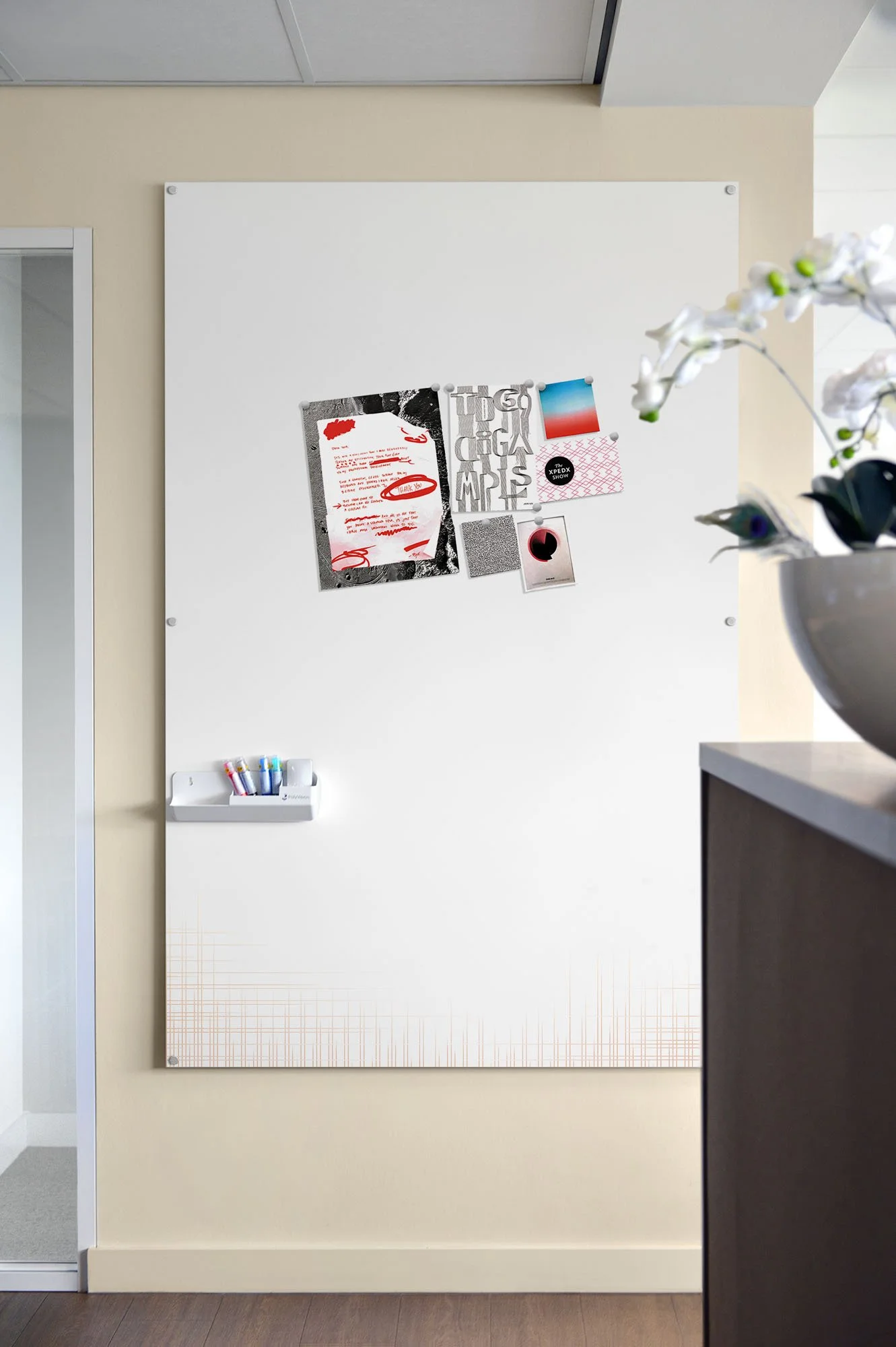 PolyVision CeramicSteel whiteboard with various papers, notes, and pictures pinned, and markers in a holder, mounted on a wall in an office.