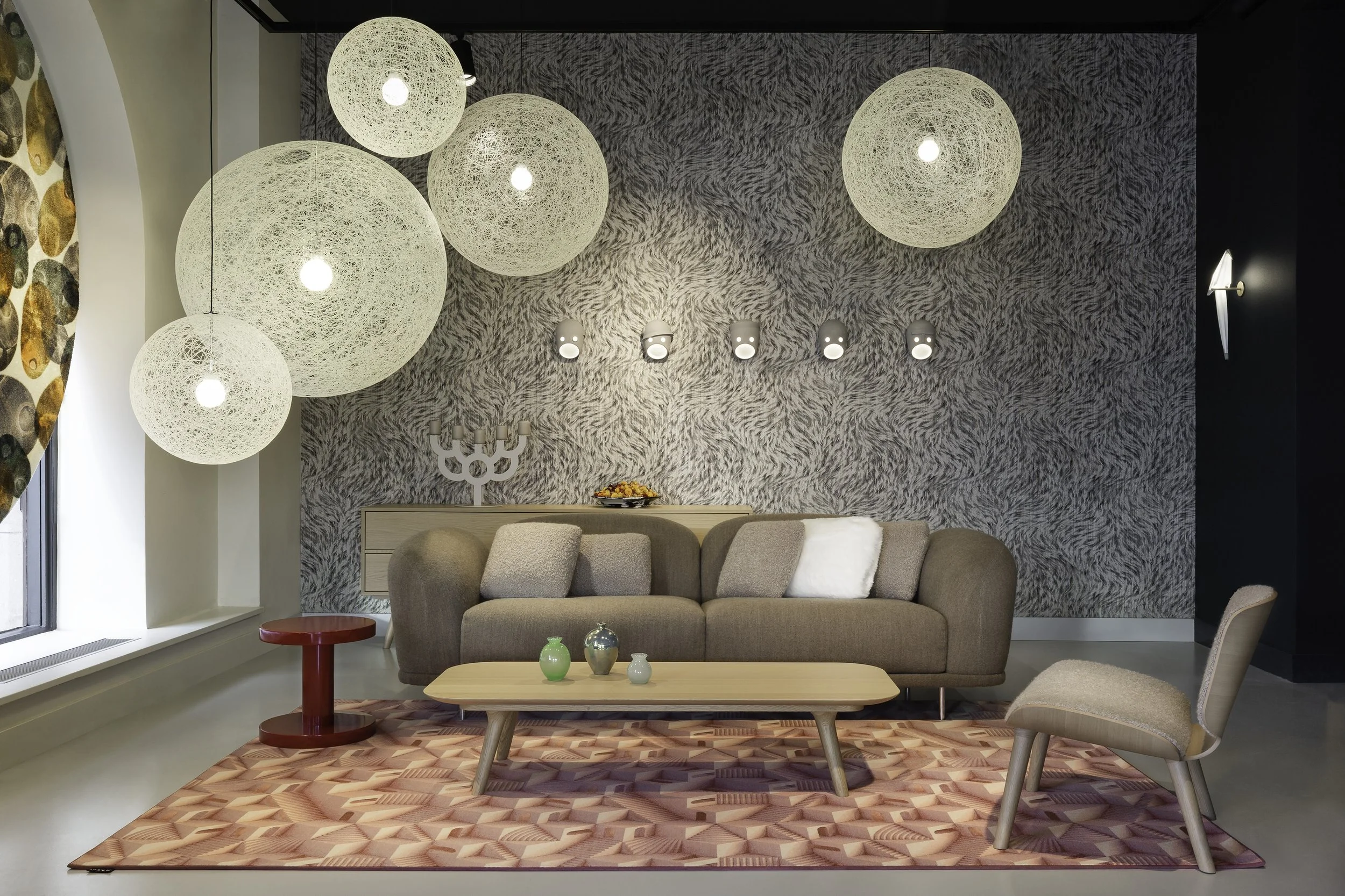 Modern living room with beige sofa, accent chair, wooden coffee table with a patterned Moooi Carpets rug.