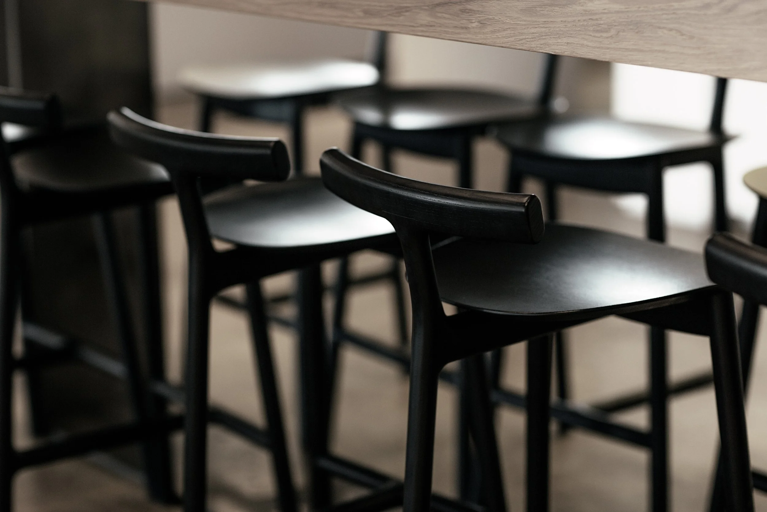 Black chairs arranged around a wooden table in a modern cafe or restaurant.