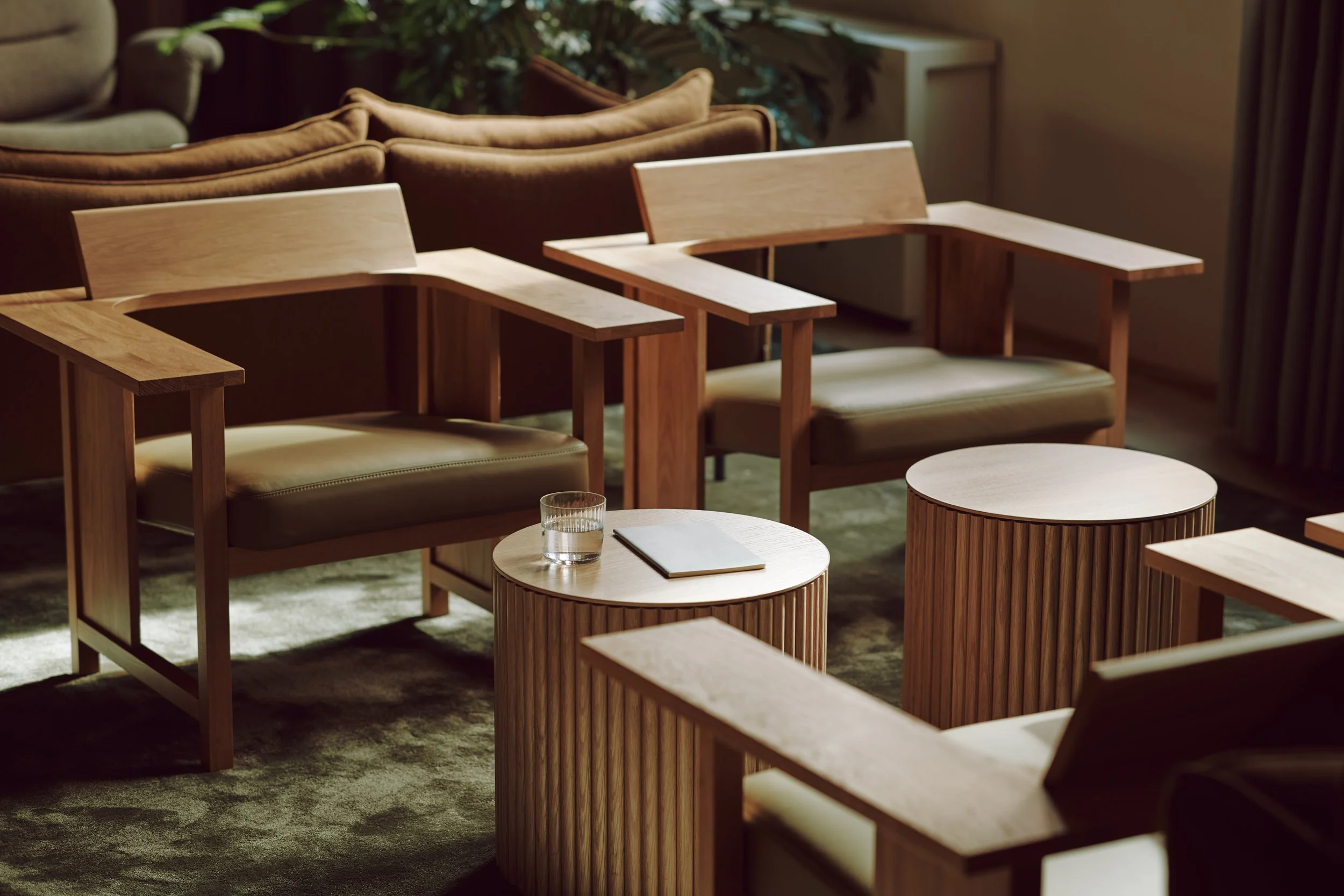 Lounge or waiting area featuring Mattiazzi wooden chairs and circular side tables with minimalist design.